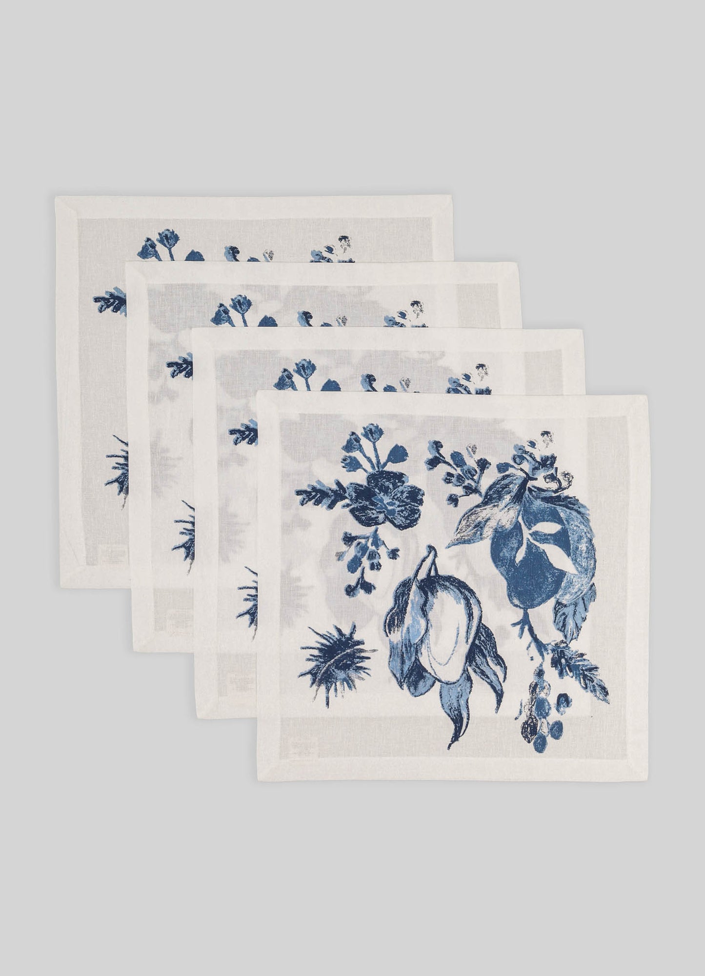 Set of five white linen napkins with blue floral prints, featuring botanical motifs and a delicate border, arranged on a light gray background.