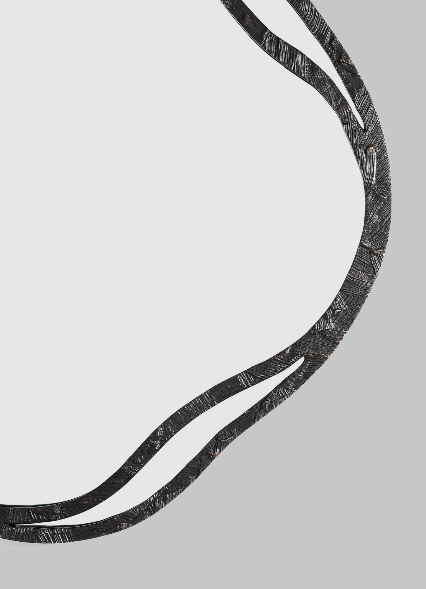 A black, textured metal mirror with a wavy, organic frame design, set against a light gray background.