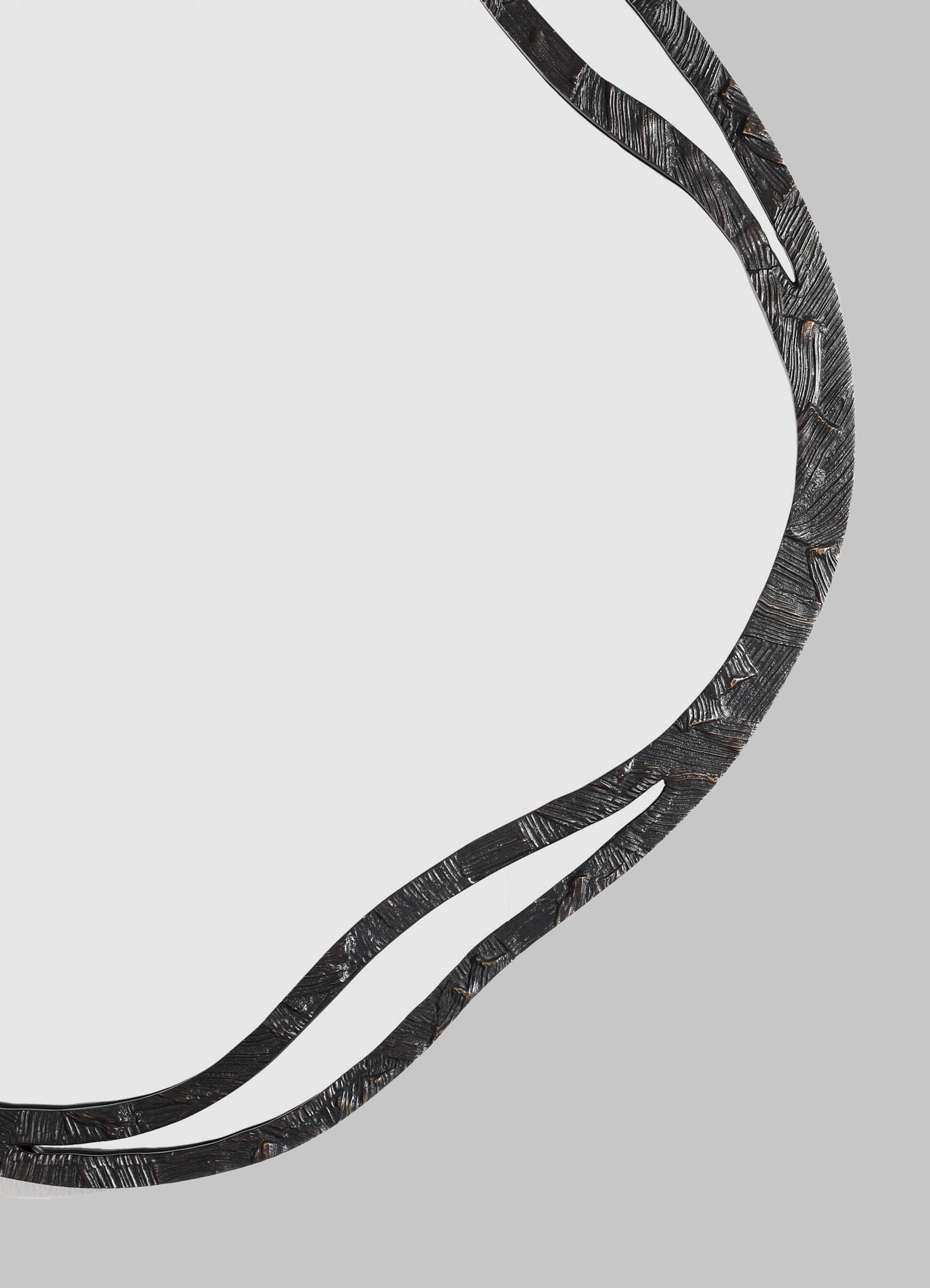 A black, textured metal mirror with a wavy, organic frame design, set against a light gray background.