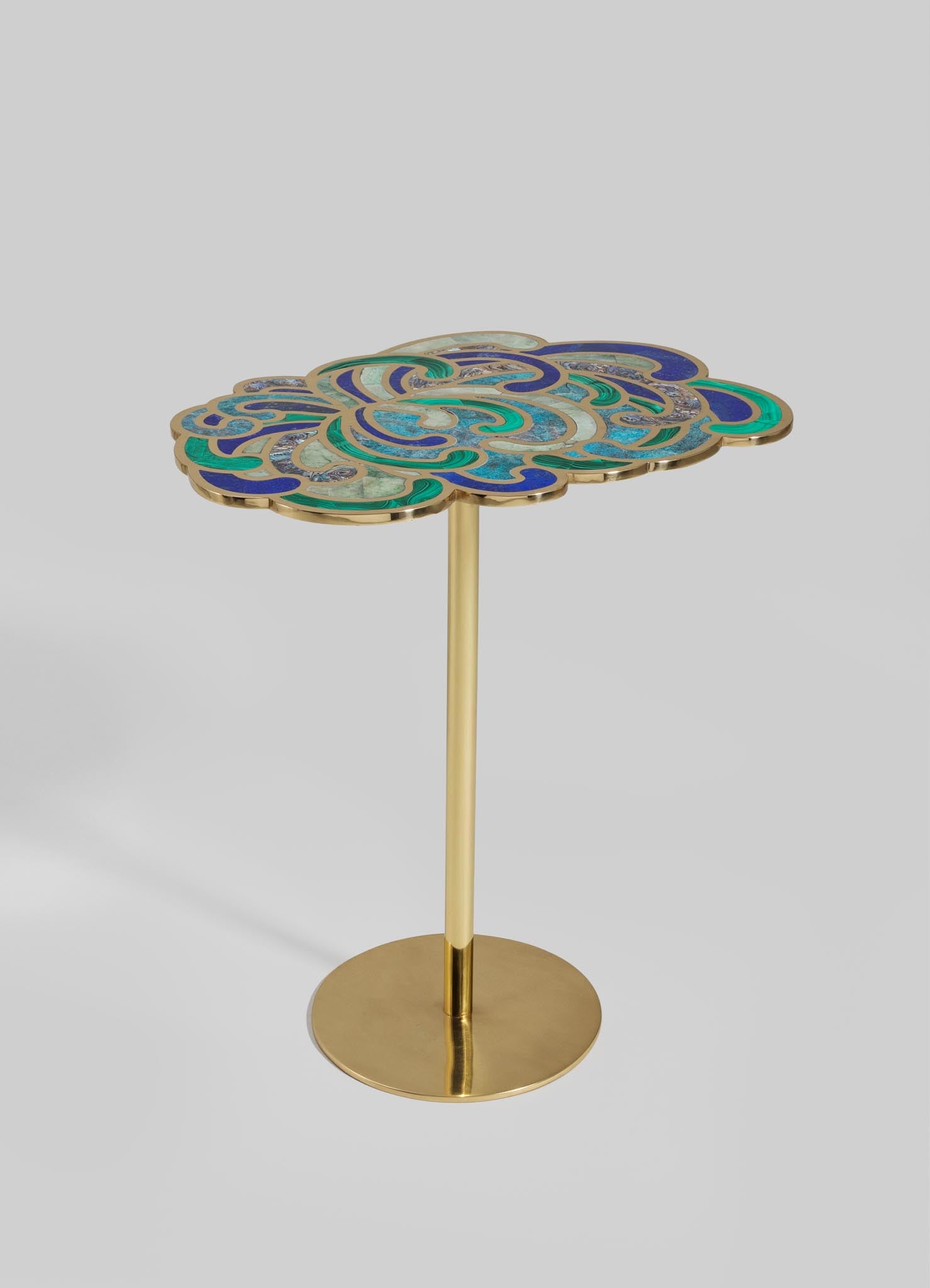 A decorative side table featuring a brass base and a tabletop with a colorful mosaic pattern of swirling shapes in shades of blue, turquoise, and cream. The style is contemporary with an artistic motif, emphasizing intricate craftsmanship.