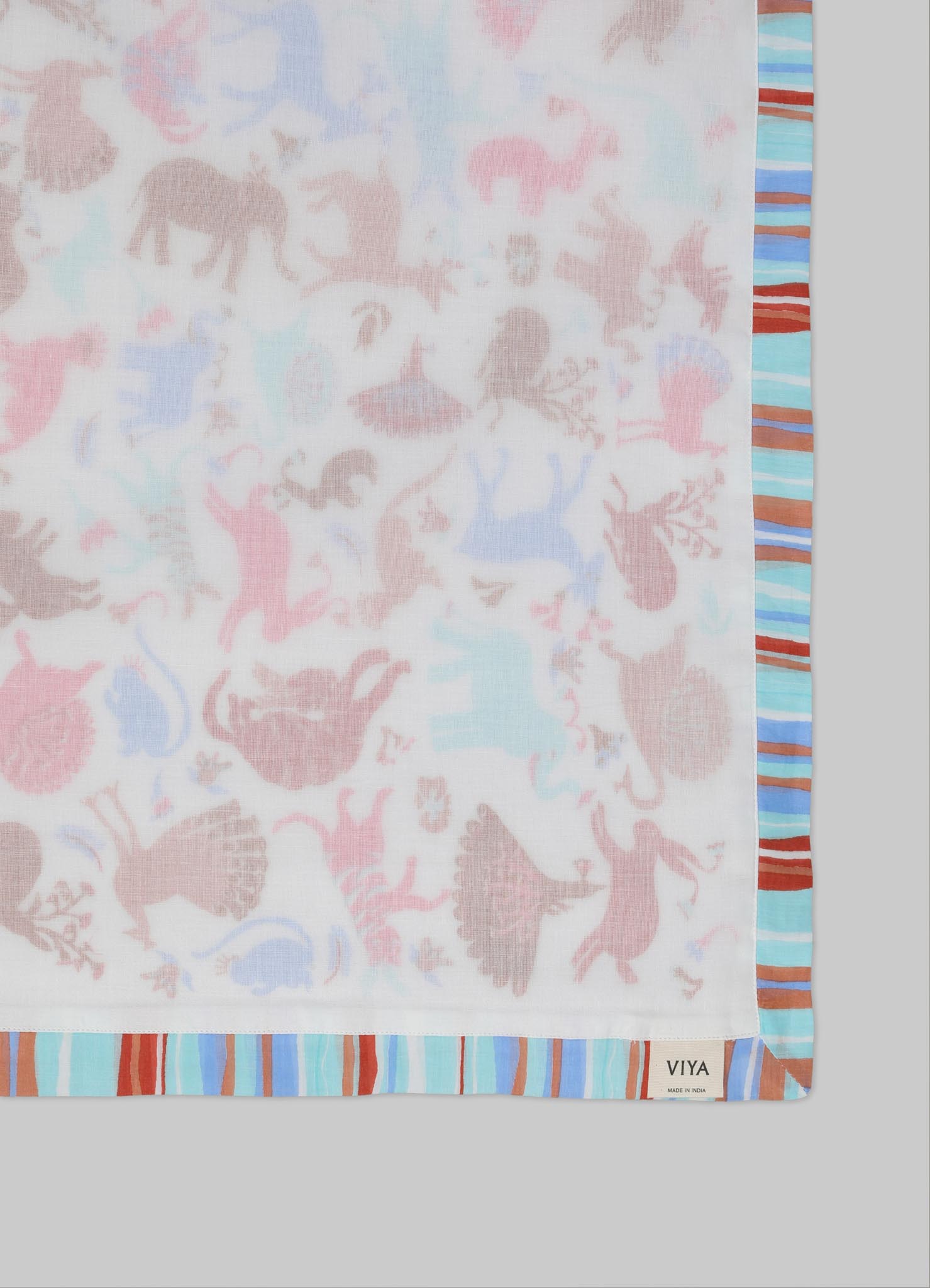 A fabric with a whimsical animal and fairy motif in soft pastel tones, bordered by a striped pattern in shades of blue, brown, and white. The material appears lightweight and printed with a delicate, casual design.