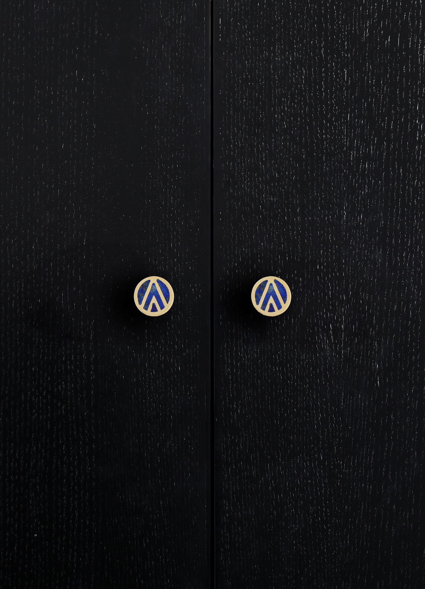 Black wooden cabinet doors with a textured finish and round knobs featuring a blue and beige graphic pattern.