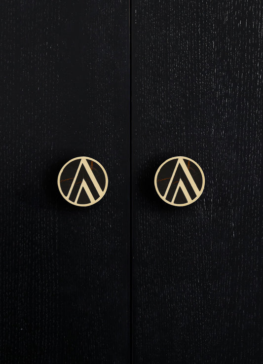 Black wooden cabinet with a textured finish and round brass knobs featuring a geometric cutout pattern.
