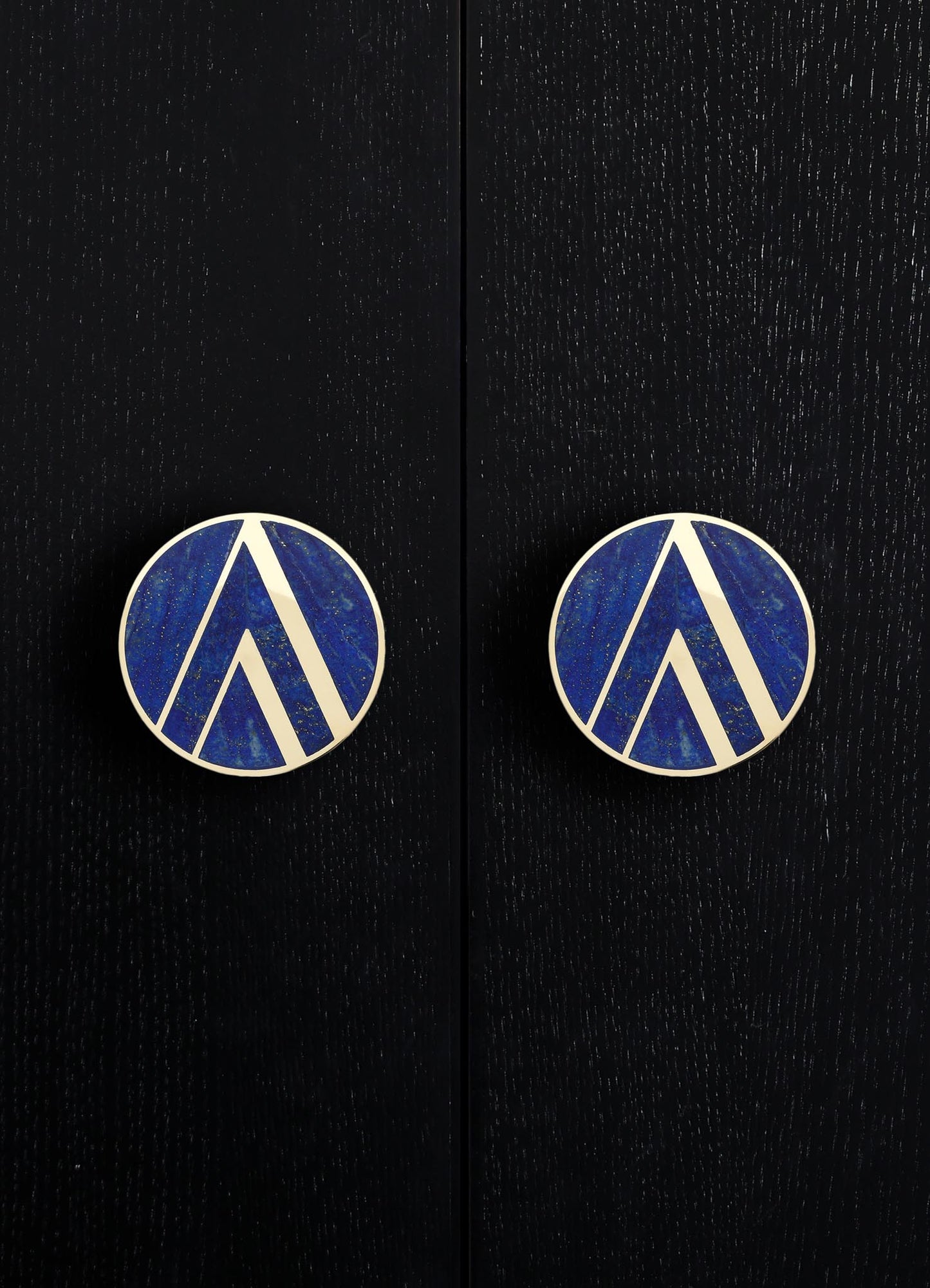 Round drawer pulls with blue and white geometric pattern, mounted on a black wooden surface.
