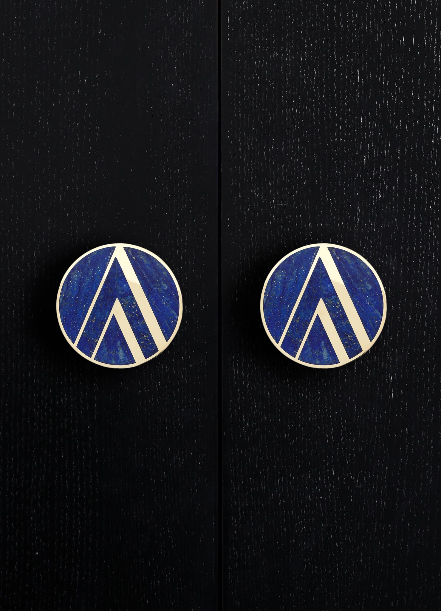 Round drawer pulls with blue and white geometric pattern, mounted on a black wooden surface.