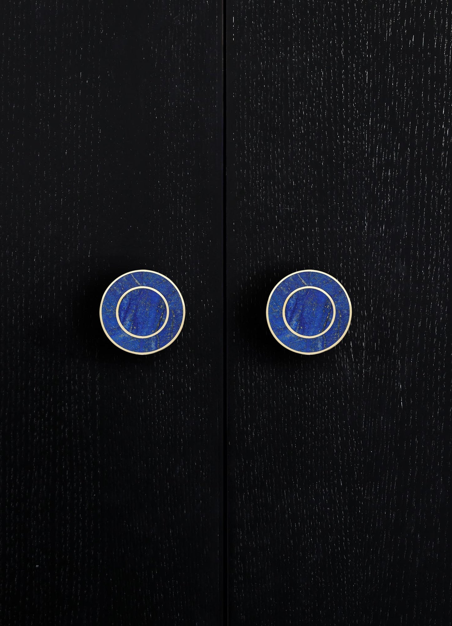 Black wooden doors with visible grain texture, featuring round blue and white ceramic knobs with concentric circle patterns. The style appears modern with a focus on clean lines and contrasting colors.