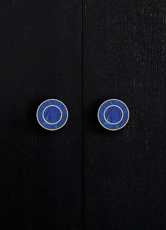 Black wooden doors with visible grain texture, featuring round blue and white ceramic knobs with concentric circle patterns. The style appears modern with a focus on clean lines and contrasting colors.
