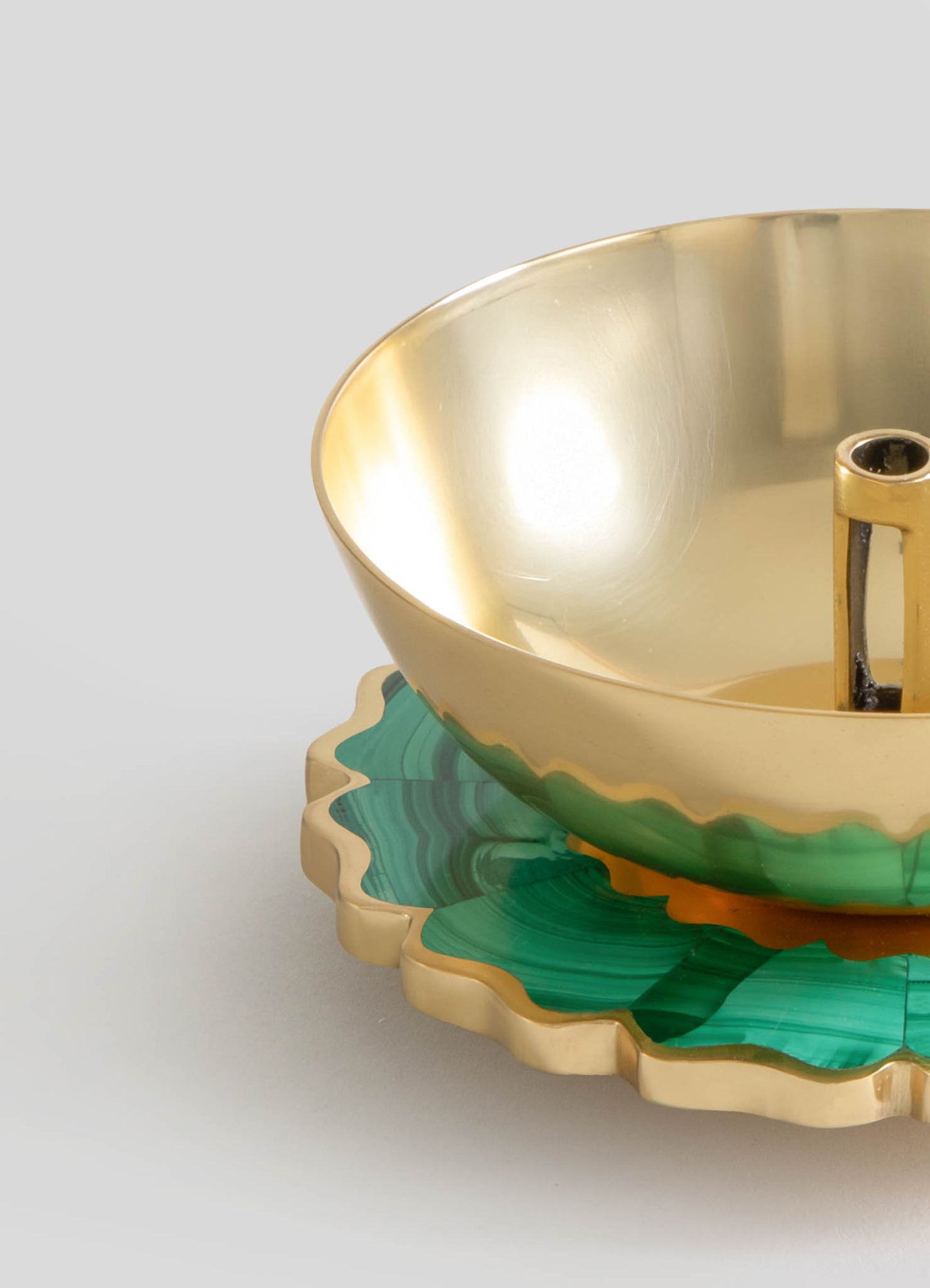 A decorative bowl with a metallic gold interior and a green and beige marbled edge, resting on a sculpted matching base. The piece features a polished, smooth surface with an elegant, contemporary design.