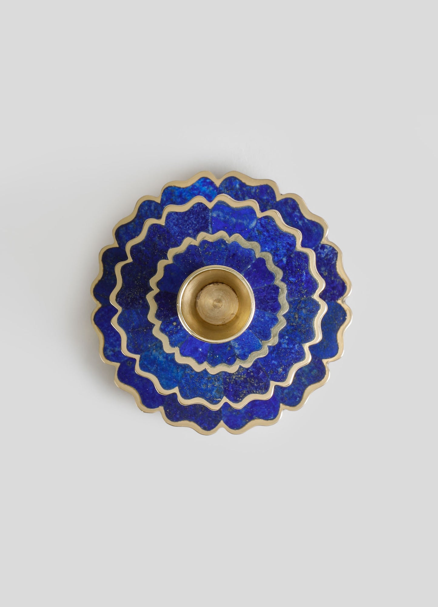A decorative blue glass bowl with scalloped edges and gold trim, featuring a floral motif and a glossy finish. The bowl has a central gold-colored lining, emphasizing its luxurious and handcrafted style.