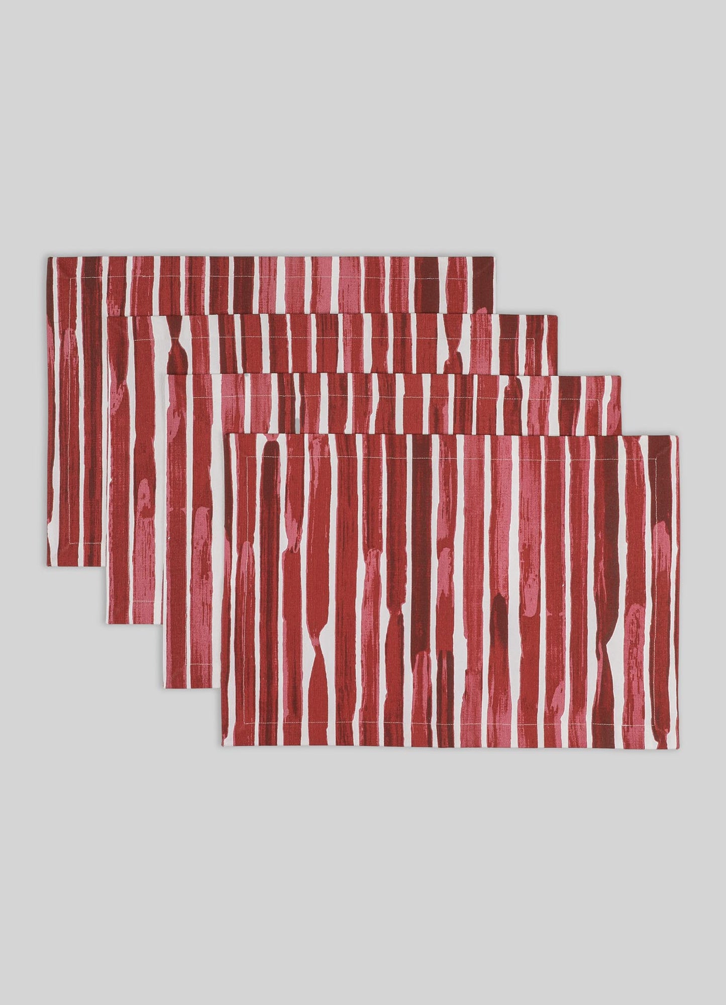 Set of four table linen placemats featuring bold red and white vertical stripe patterns on a neutral gray background. The placemats are made from a fabric with a contemporary, graphic style.