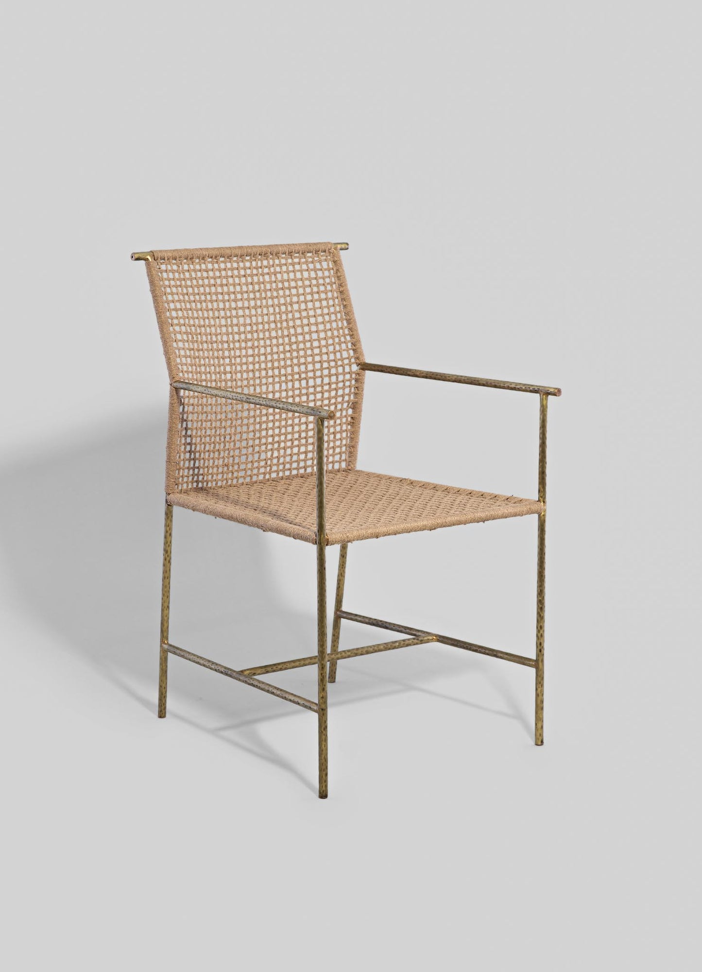 Wicker armchair with a metal frame finished in brass, featuring a woven rattan seat and backrest in natural beige tones, with slender armrests and a minimalist design.