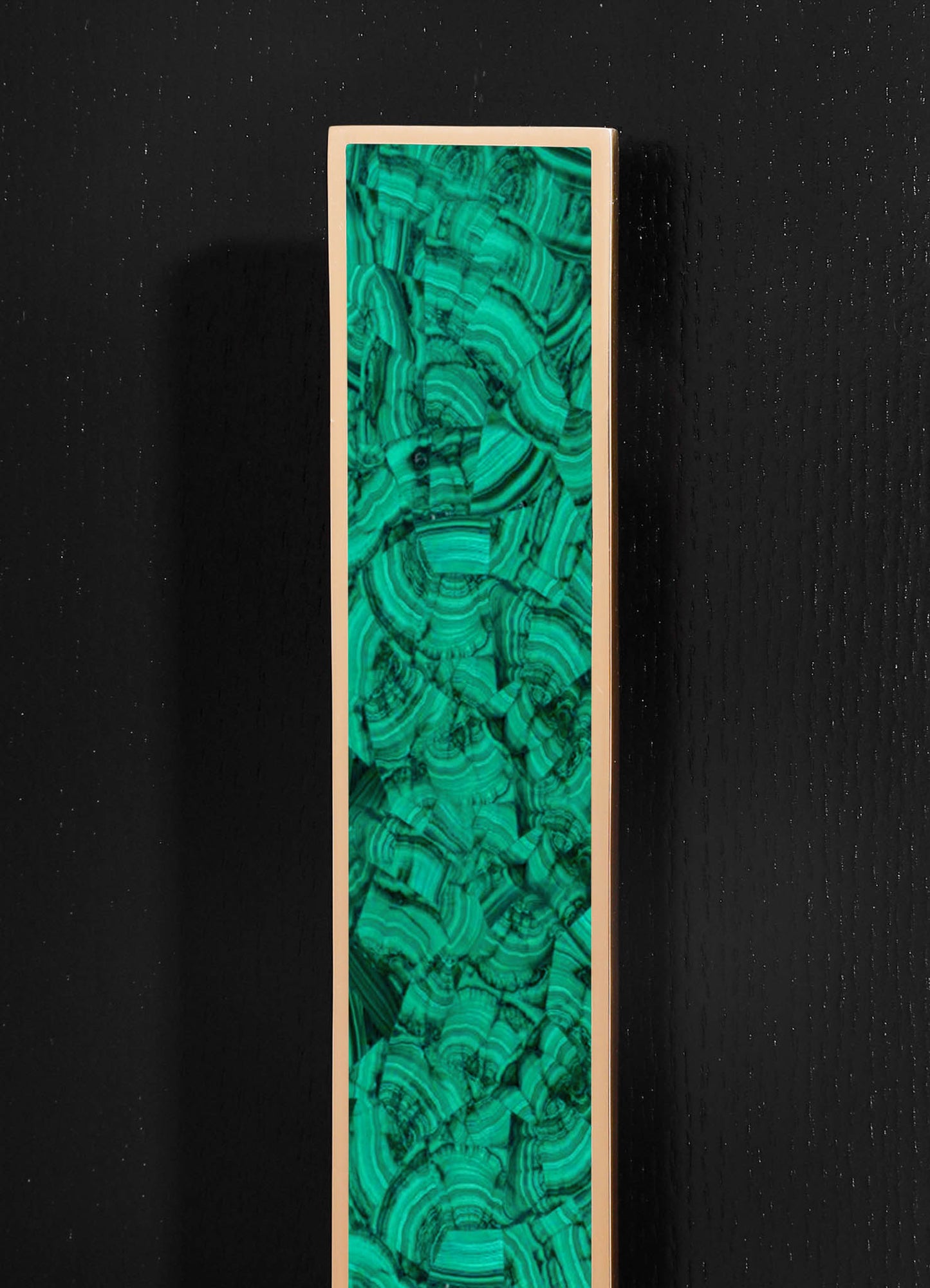 A tall decorative panel with a vibrant green and black swirling malachite pattern, framed in a smooth, light-colored border, set against a black textured background.