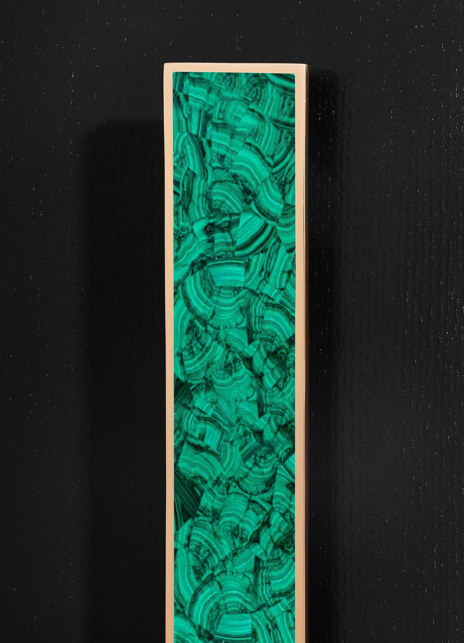 A tall decorative panel with a vibrant green and black swirling malachite pattern, framed in a smooth, light-colored border, set against a black textured background.