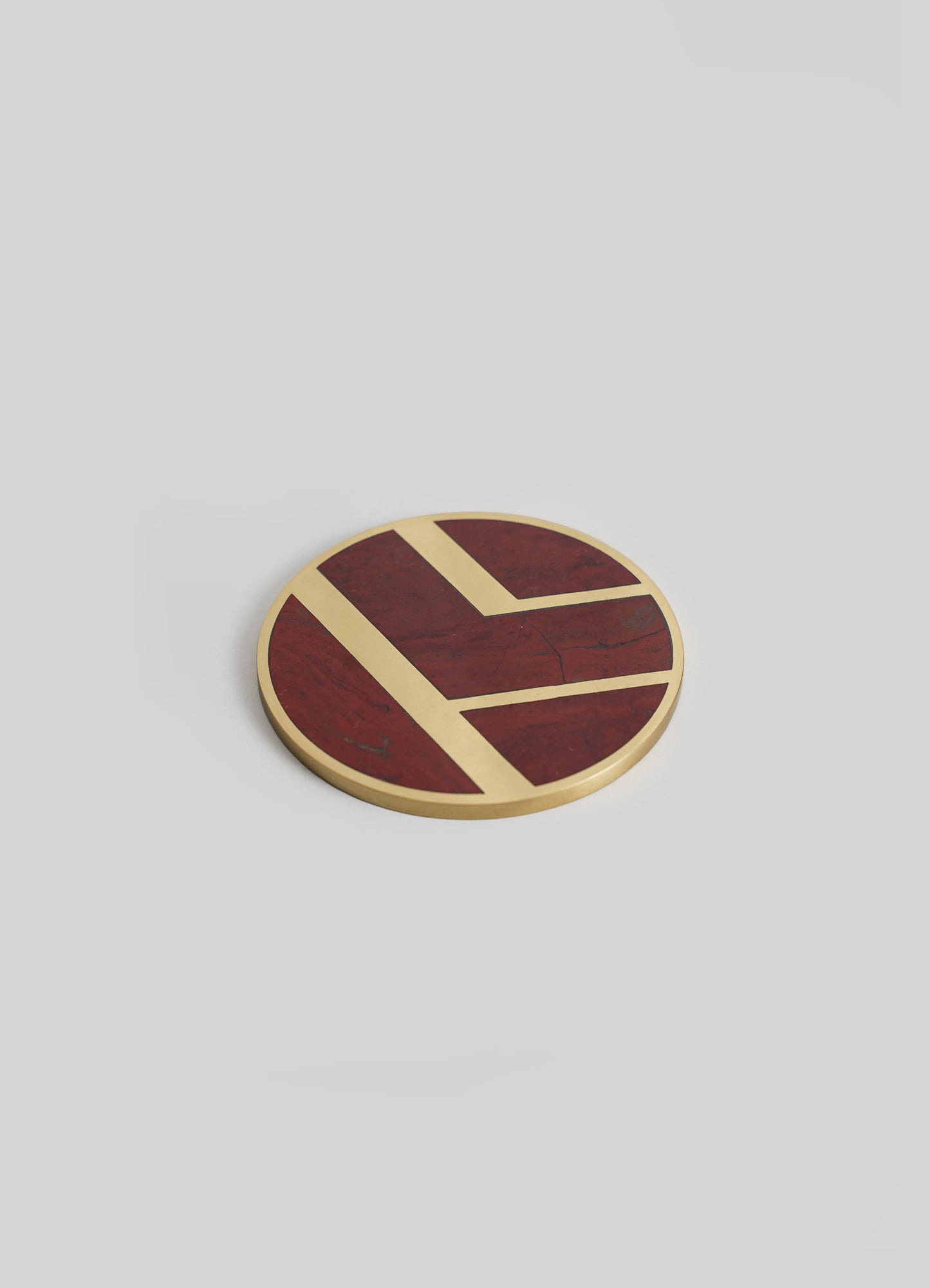 A round wooden coaster with geometric pattern in dark red and beige tones, featuring a smooth finish and minimalist design.