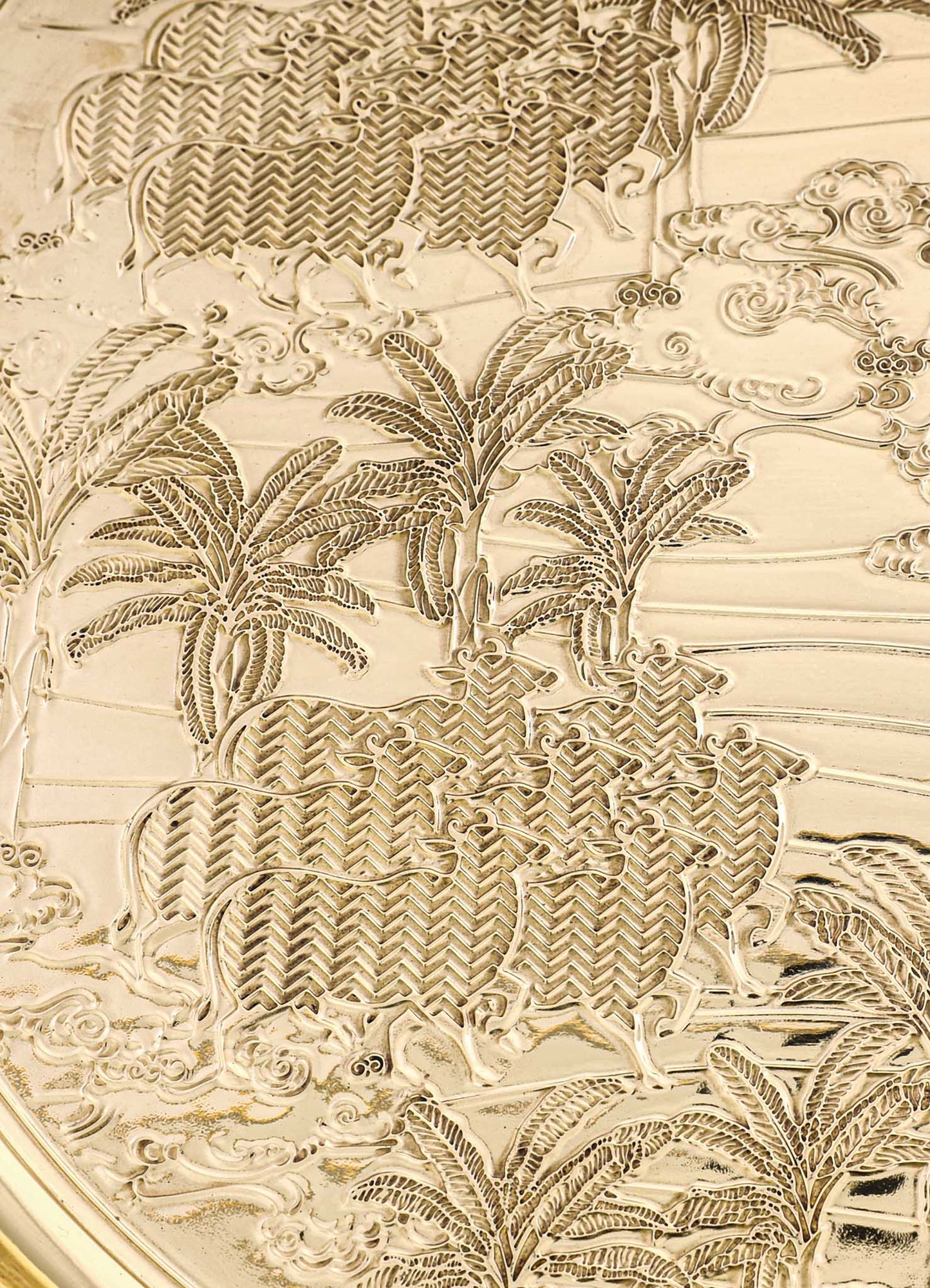 Decorative metal tray with intricate embossed patterns of palm trees, animals, and swirling motifs in a gold-tone finish, featuring a detailed and ornate design style.