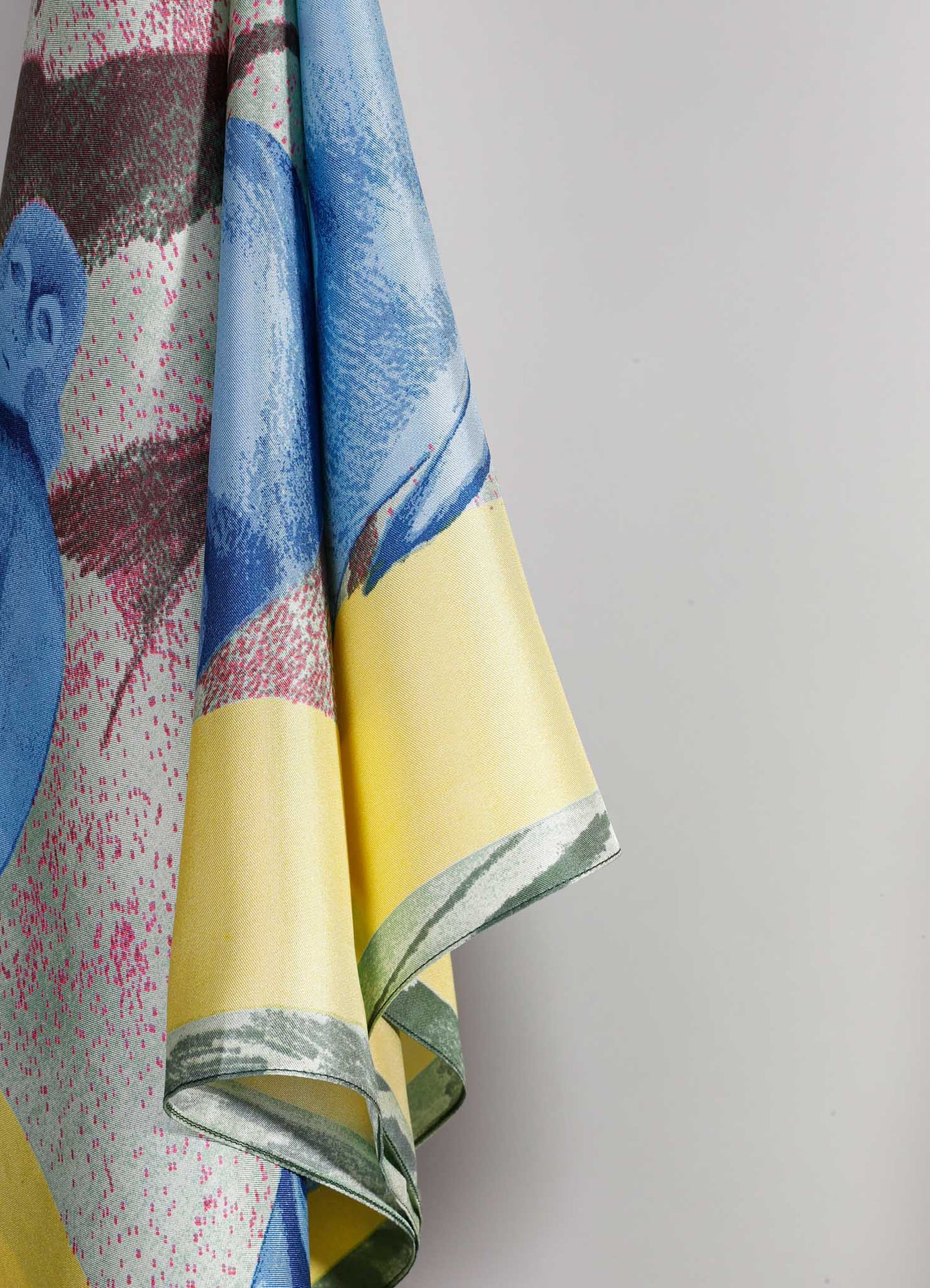 Colorful silk fabric with a floral motif in shades of yellow, blue, pink, and green, featuring a smooth, shiny texture. The fabric appears to be lightweight and draped, with a contemporary and vibrant aesthetic.