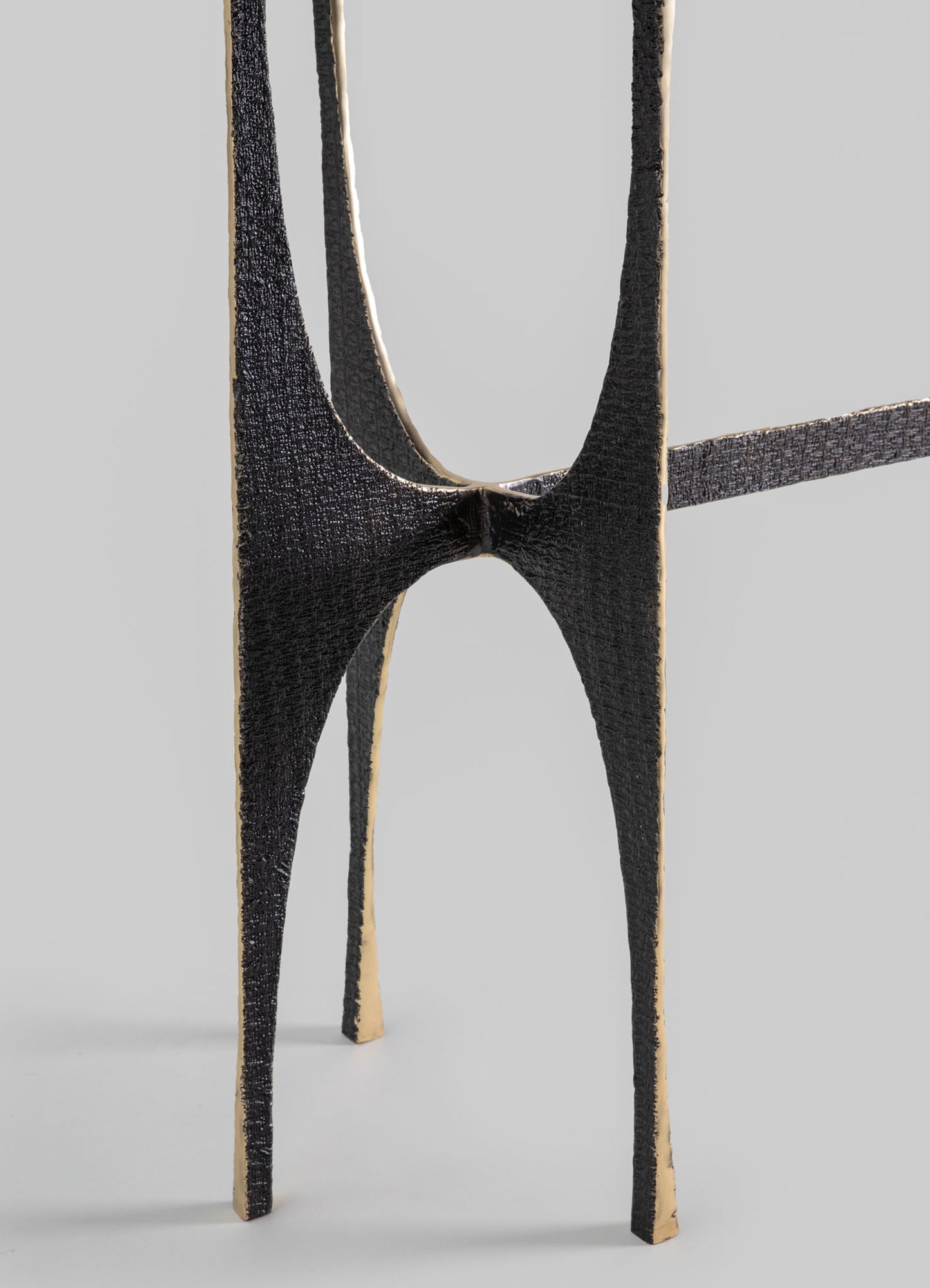 A black wooden chair with a distinctive cut-out backrest and tapered legs, featuring a textured finish and contrasting beige accents along the edges, in a minimalist setting.