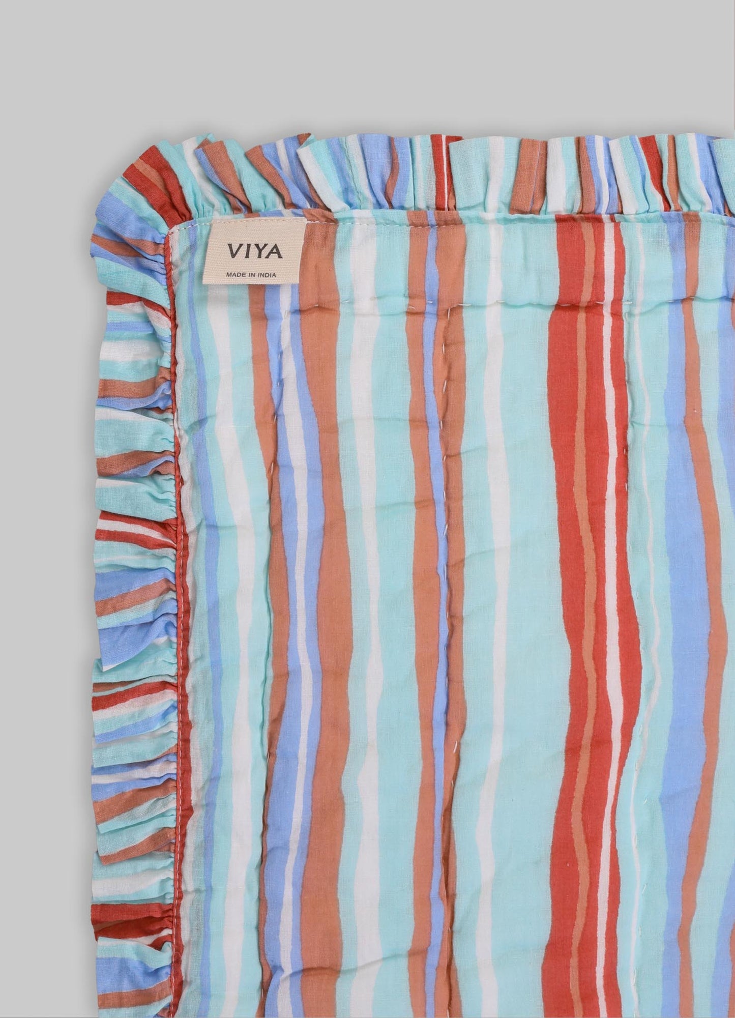 Striped fabric cushion cover with ruffled edges in pastel shades of blue, orange, red, white, and brown linen blend material.