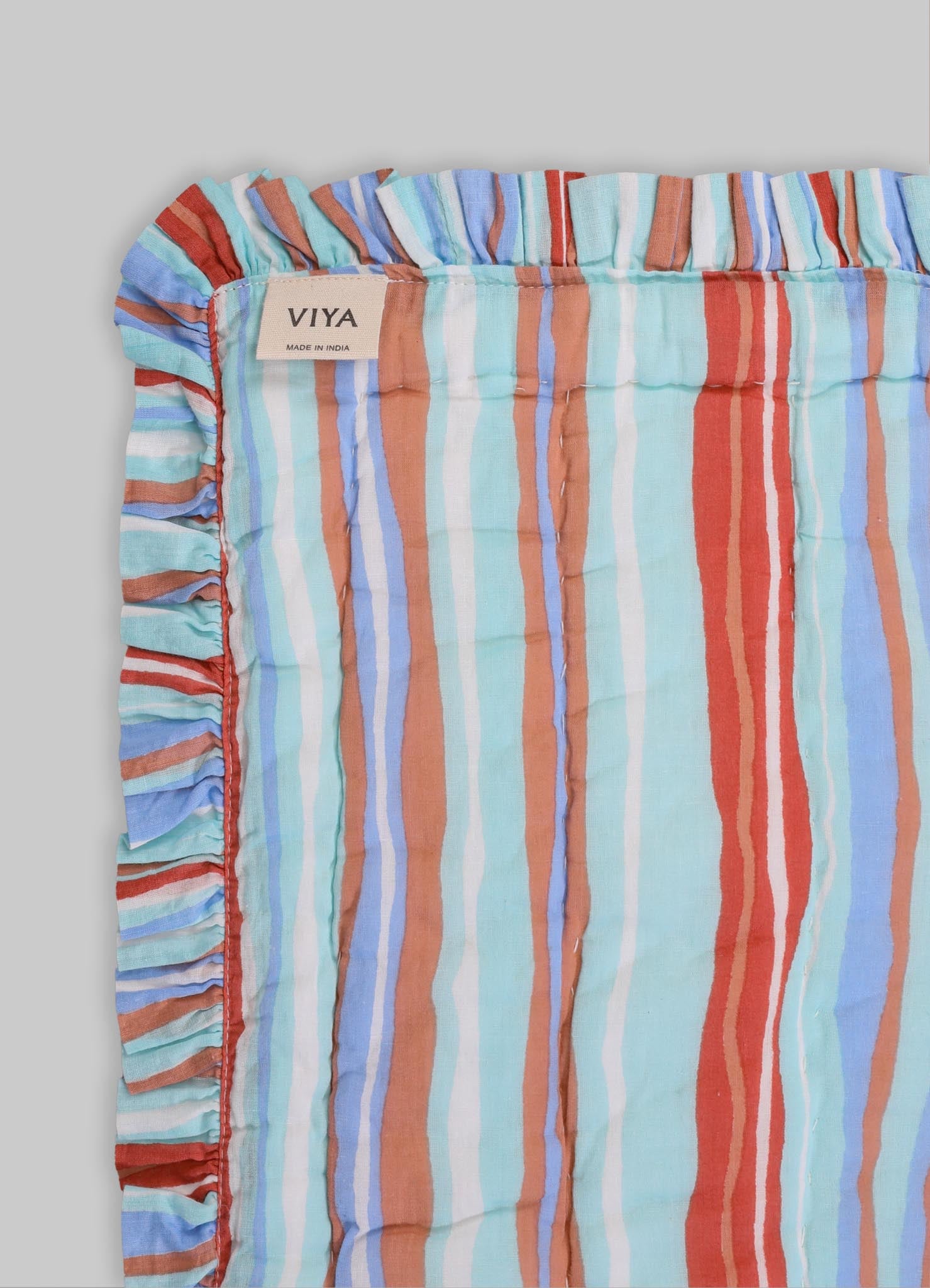 Striped fabric cushion cover with ruffled edges in pastel shades of blue, orange, red, white, and brown linen blend material.