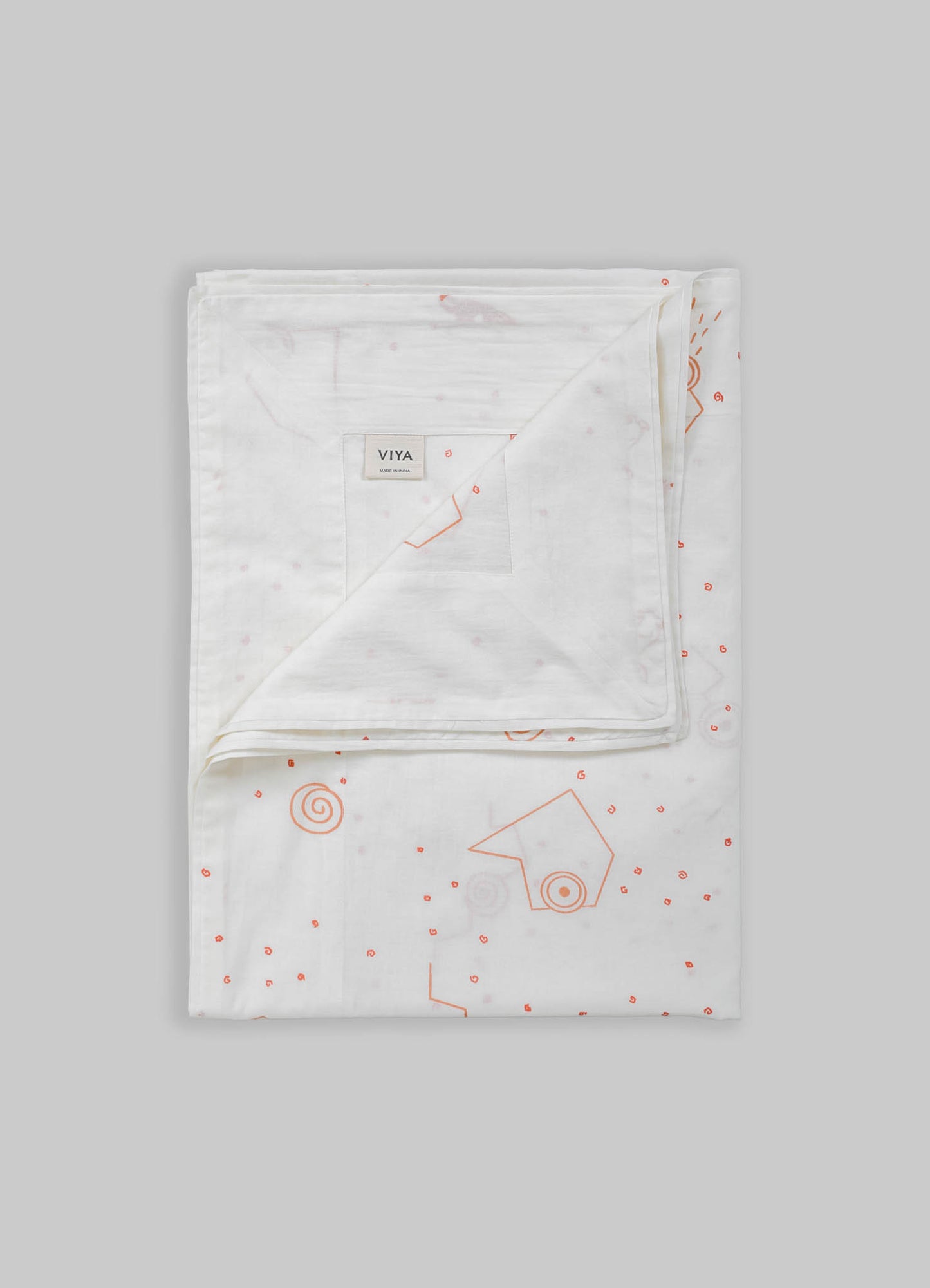 White bed linen set made of cotton with subtle pink and orange geometric and spiral motifs, featuring a duvet cover and pillowcases. The design is contemporary and minimalist with a soft, light-toned background.