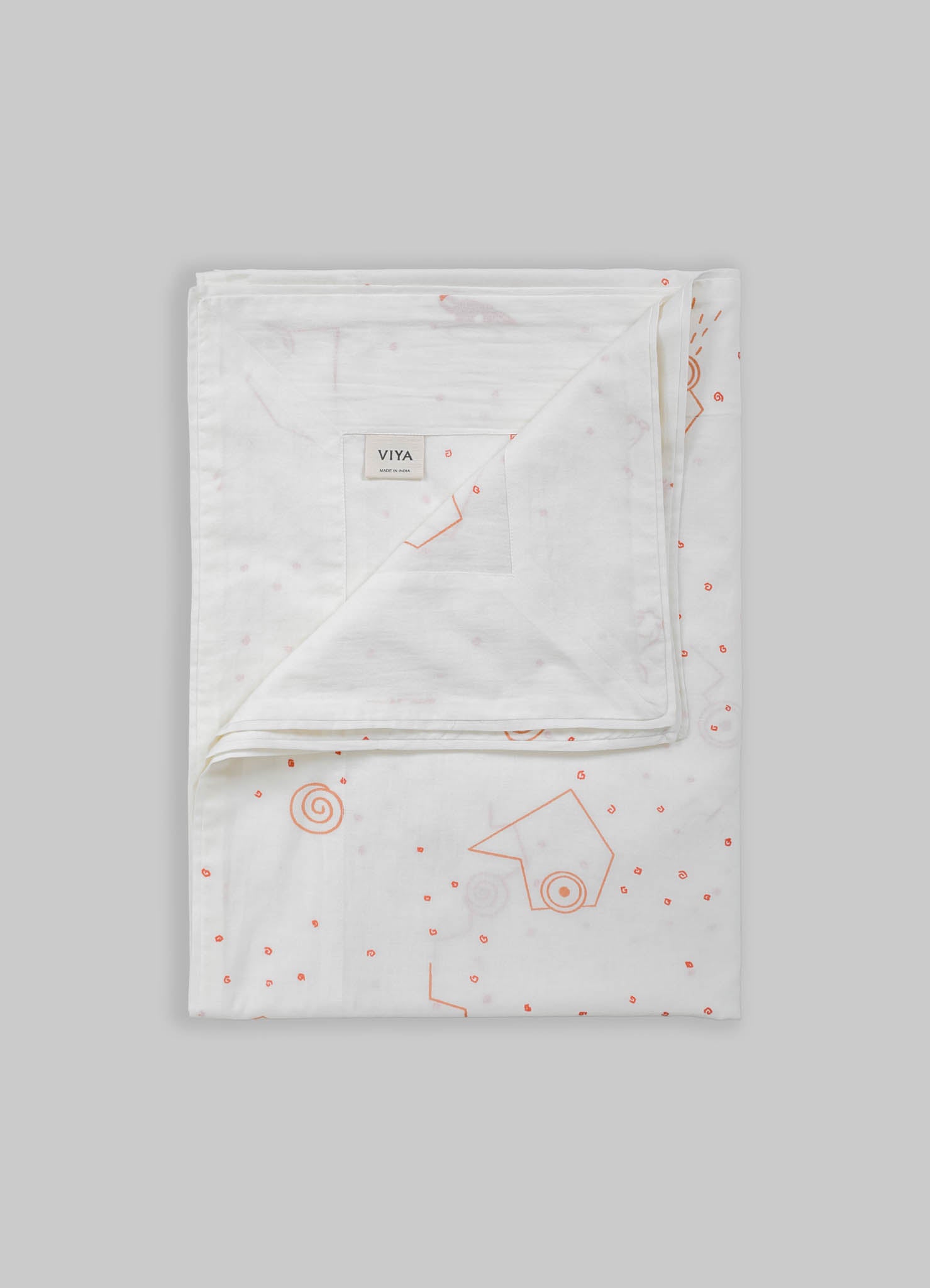 White bed linen set made of cotton with subtle pink and orange geometric and spiral motifs, featuring a duvet cover and pillowcases. The design is contemporary and minimalist with a soft, light-toned background.