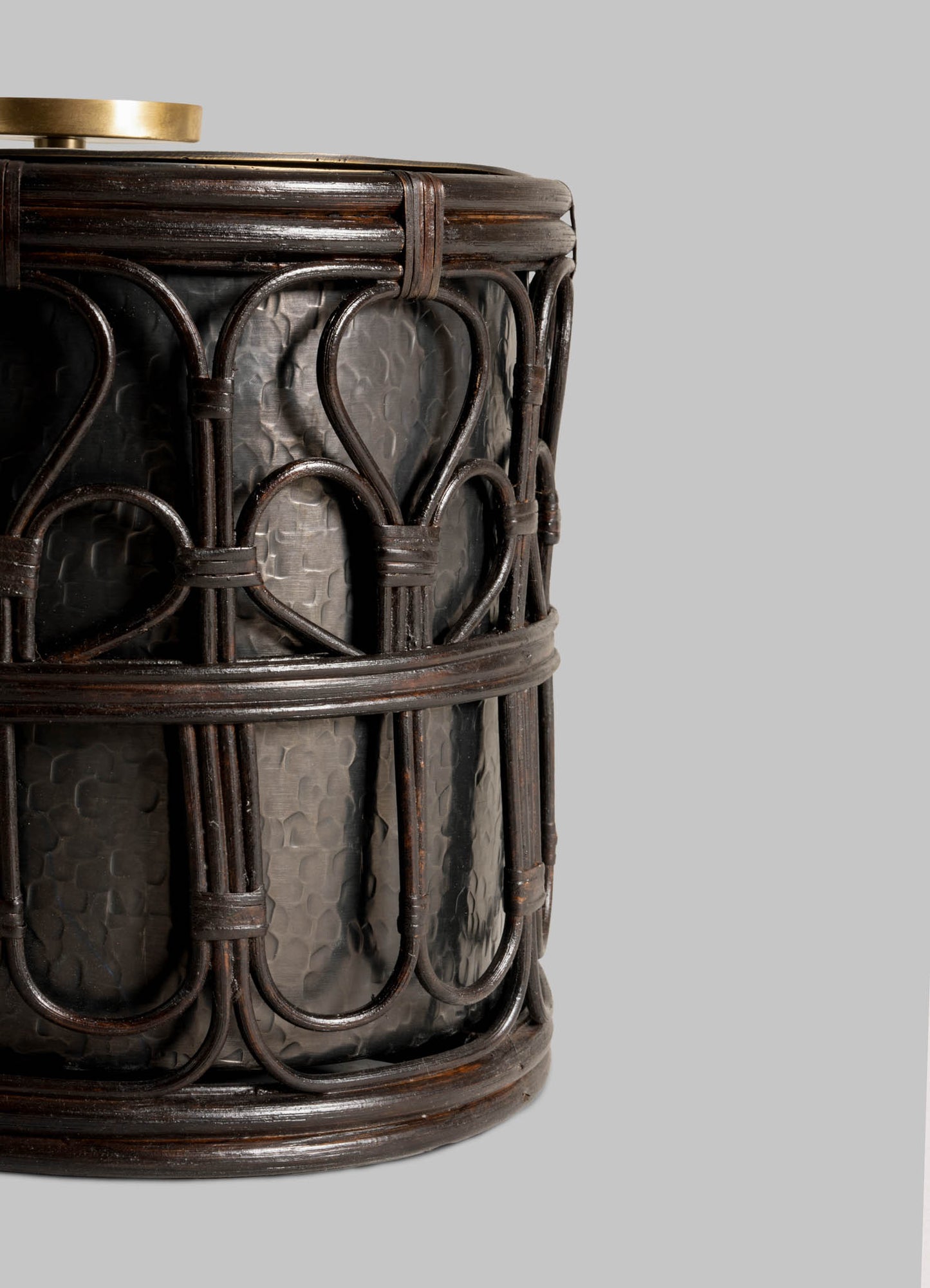 Close-up of the VIYA Manipur Ice Bucket Large—a dark, cylindrical container with intricate cane lattice and hand-beaten brass, perfect as a stylish barware accessory—shown against a plain light gray background.