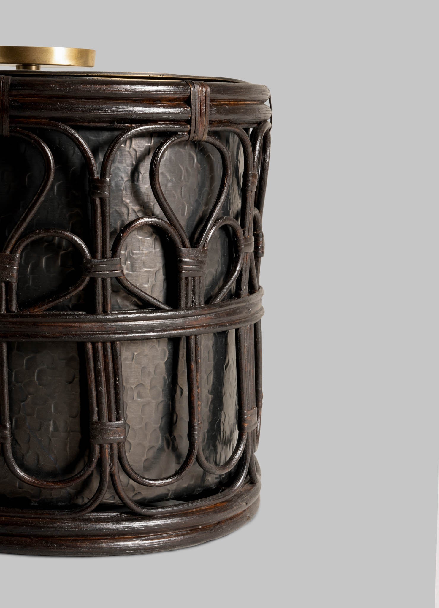 Close-up of the VIYA Manipur Ice Bucket Large—a dark, cylindrical container with intricate cane lattice and hand-beaten brass, perfect as a stylish barware accessory—shown against a plain light gray background.