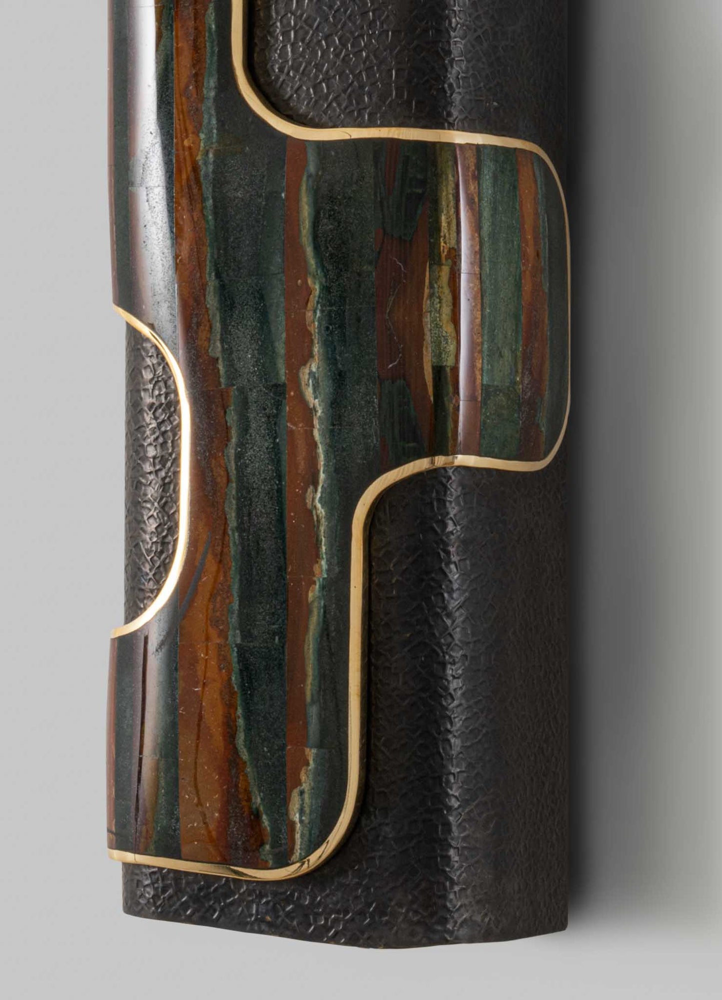 A decorative table visible in the image, featuring a top surface with a multicolored, abstract pattern in shades of green, brown, and cream, framed by a thin gold trim. The main body appears to be made of black textured material, possibly leather or faux leather, with a subtle pattern.