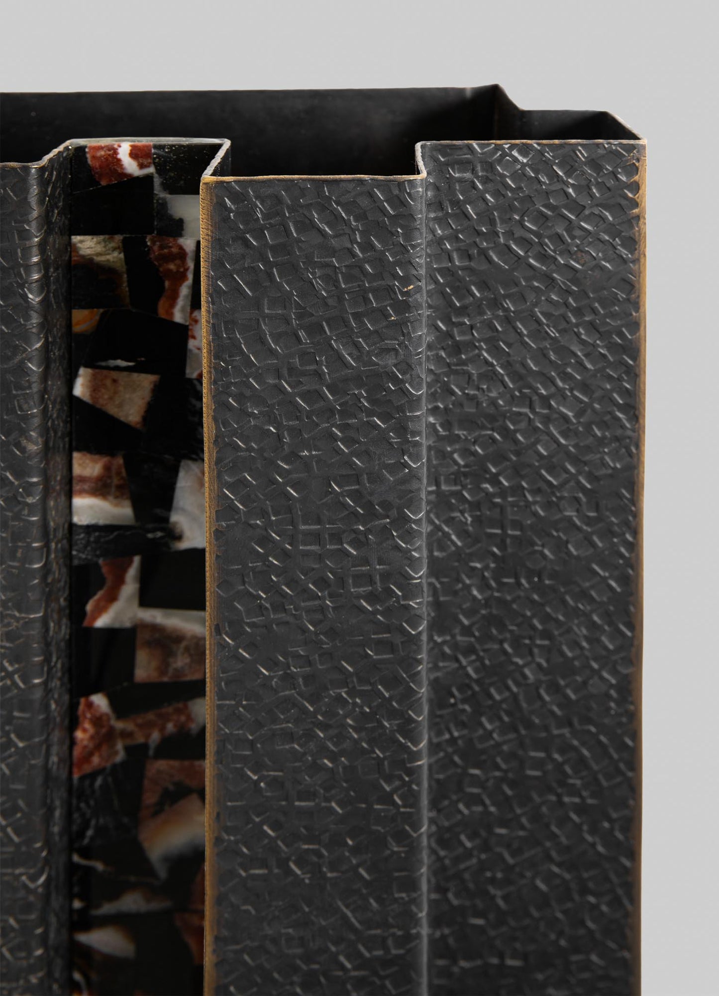A decorative book with a black textured cover featuring a geometric pattern, paired with an inner cover showcasing a multicolored mosaic design with irregular shapes and earthy tones.