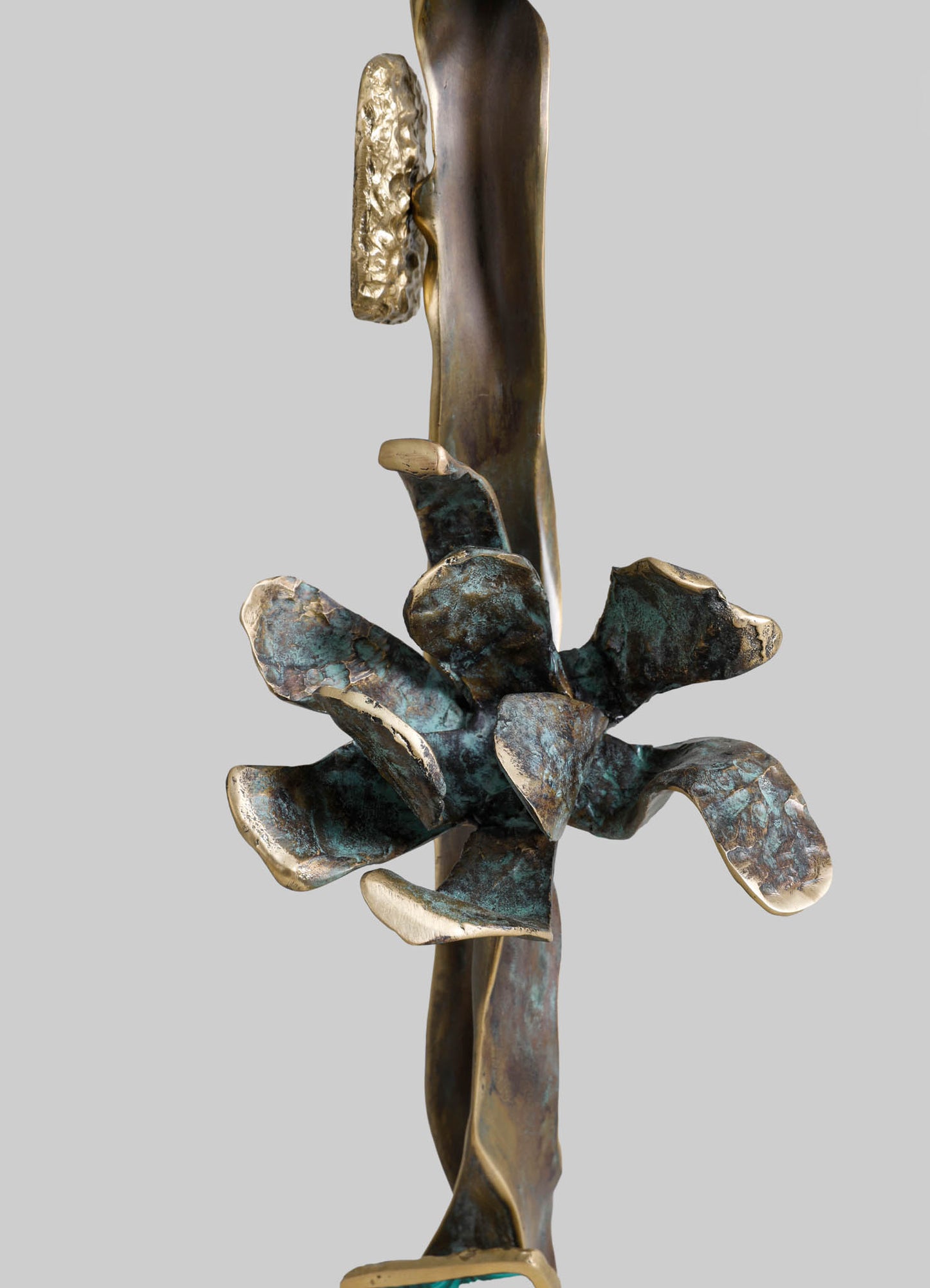 A botanical-themed sculpture crafted from metal with a bronze and aged patina finish, featuring a stylized flower with curved petals and textured details set against a plain background.