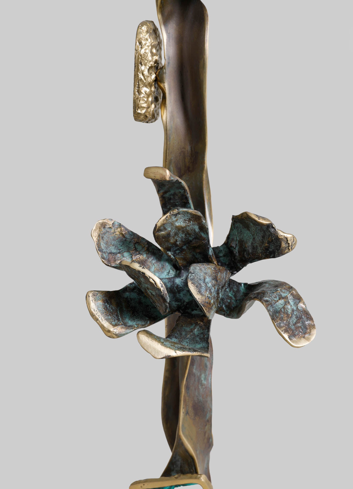 A botanical-themed sculpture crafted from metal with a bronze and aged patina finish, featuring a stylized flower with curved petals and textured details set against a plain background.