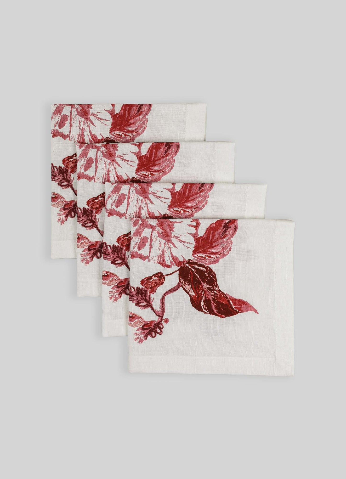 Set of four linen napkins with a floral print in shades of red on a white background, featuring a natural woven texture.