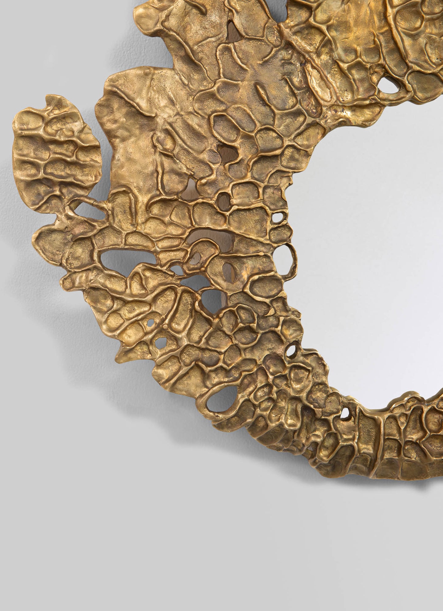 A decorative wall sculpture made of textured metal with a gold finish, featuring an abstract, organic, honeycomb-like pattern with irregular openings and a layered, sculptural form.