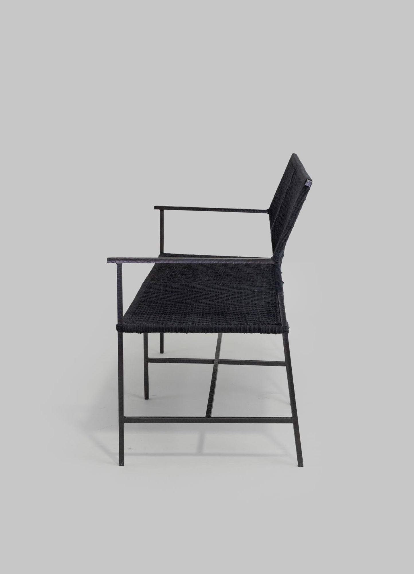 A black armchair with a woven texture, featuring a metal frame and slim armrests, set against a plain light gray background.