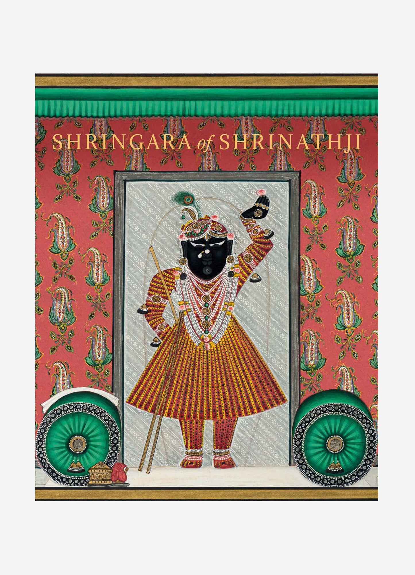 A textile featuring a traditional Indian painting of a deity, with vibrant colors and intricate motifs, mounted on a background of red patterned fabric with floral designs. The textile has decorative wheel accents and a detailed border.