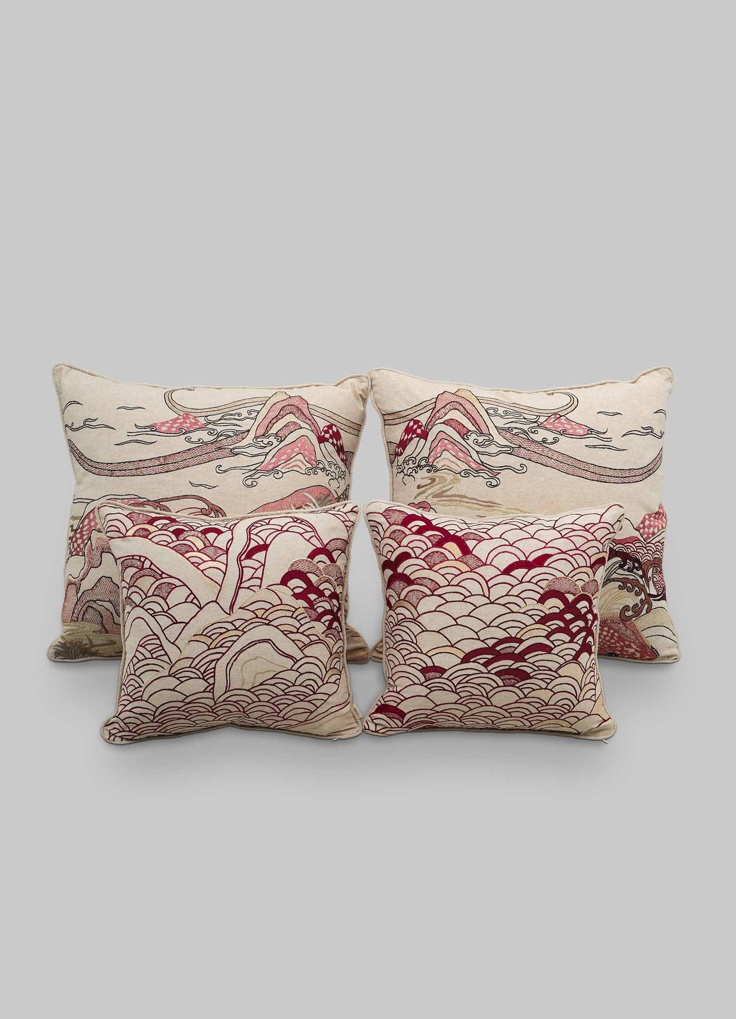 Four Viya Dreamscape Red Embroidered Cushion Covers (24"x24") with abstract red and beige wave and mountain patterns, inspired by traditional Japanese art, are arranged in two rows on a light gray background.