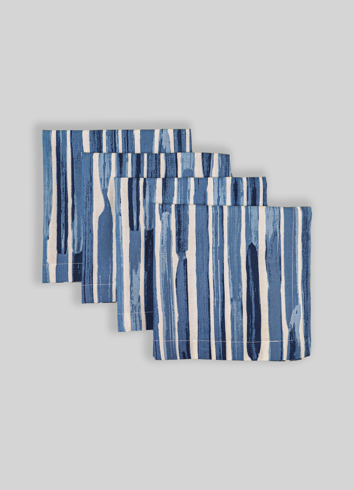 Set of four fabric placemats with blue and white vertical stripe pattern, made of woven material, arranged on a neutral background.
