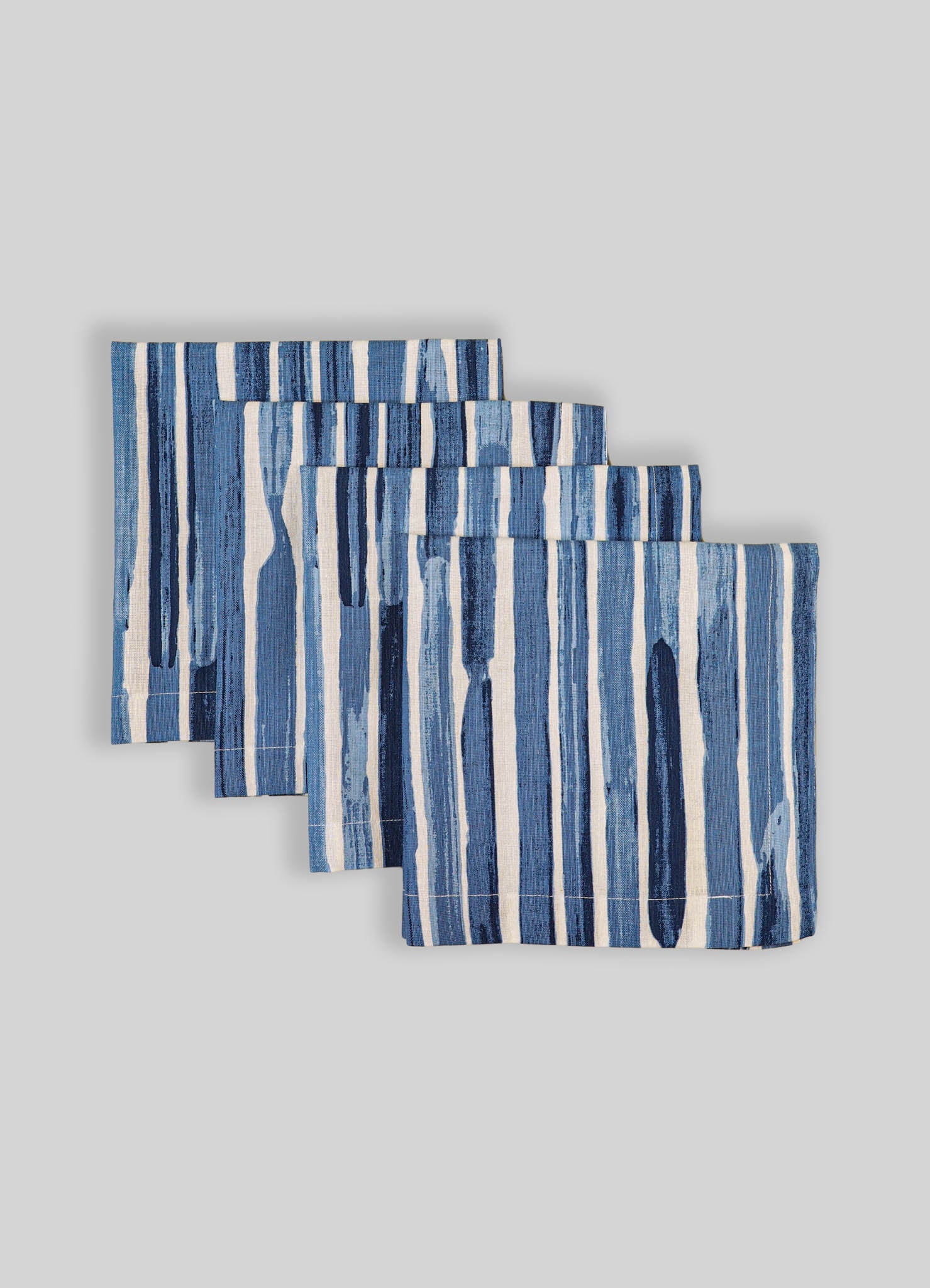 Set of four fabric placemats with blue and white vertical stripe pattern, made of woven material, arranged on a neutral background.