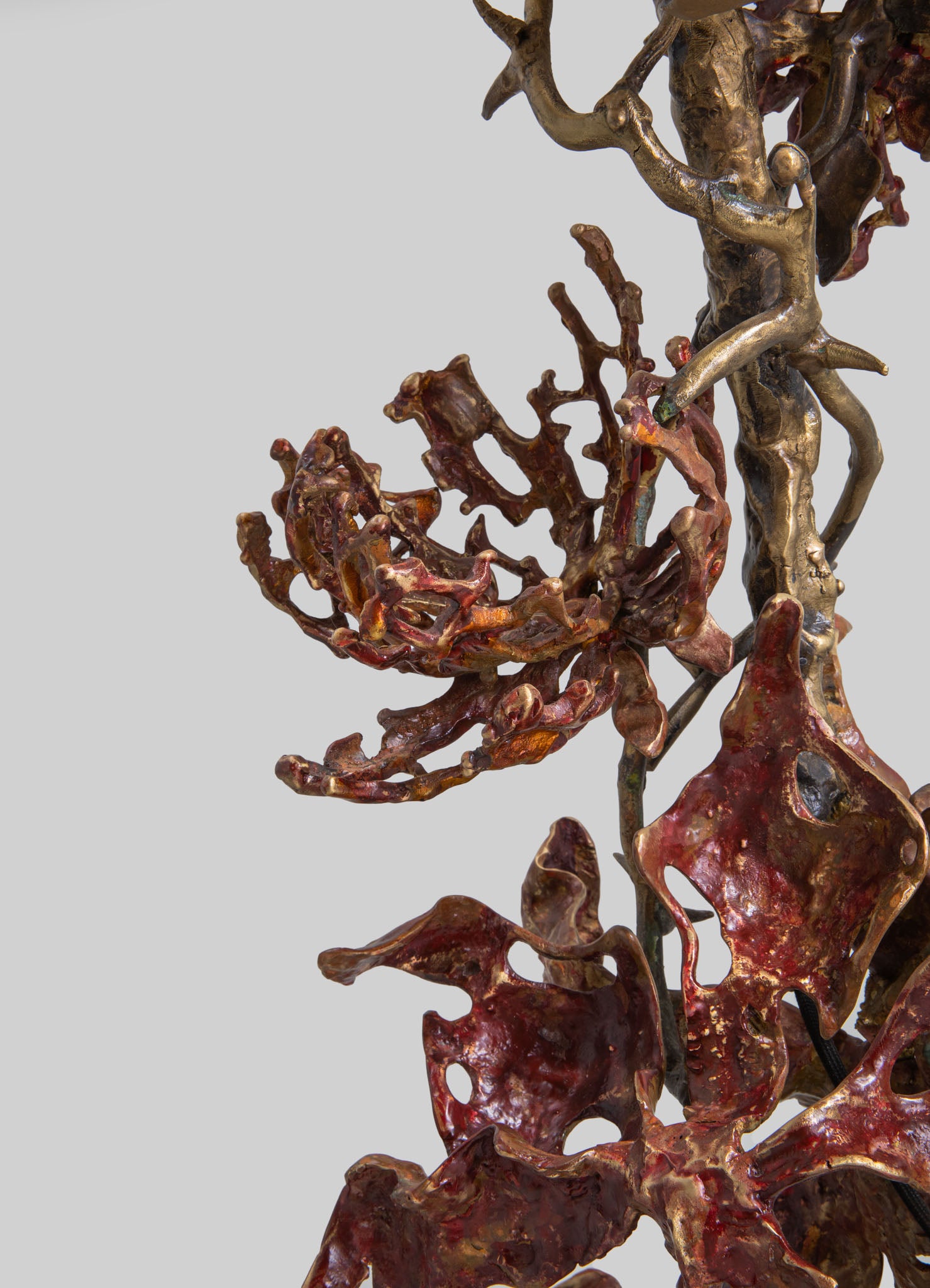 A sculptural art piece crafted from metal, featuring twisted and organic forms in bronze and reddish hues, with a highly textured surface and an abstract, natural-inspired design.