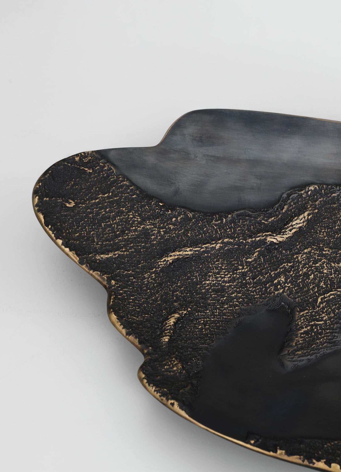 A decorative tray made of black and gold-toned material with a textured, marbled pattern and scalloped edges, featuring a contemporary and sophisticated style.