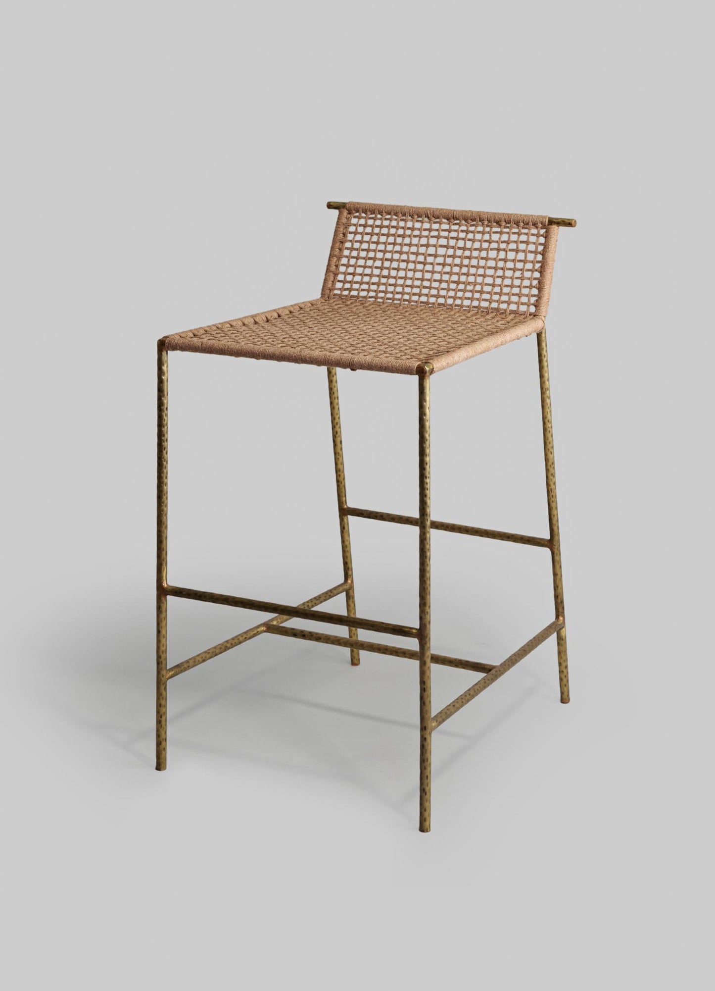 A cantilever-style chair with a woven rattan seat and backrest, featuring a brass-toned metal frame with a hammered finish and a rustic aesthetic.