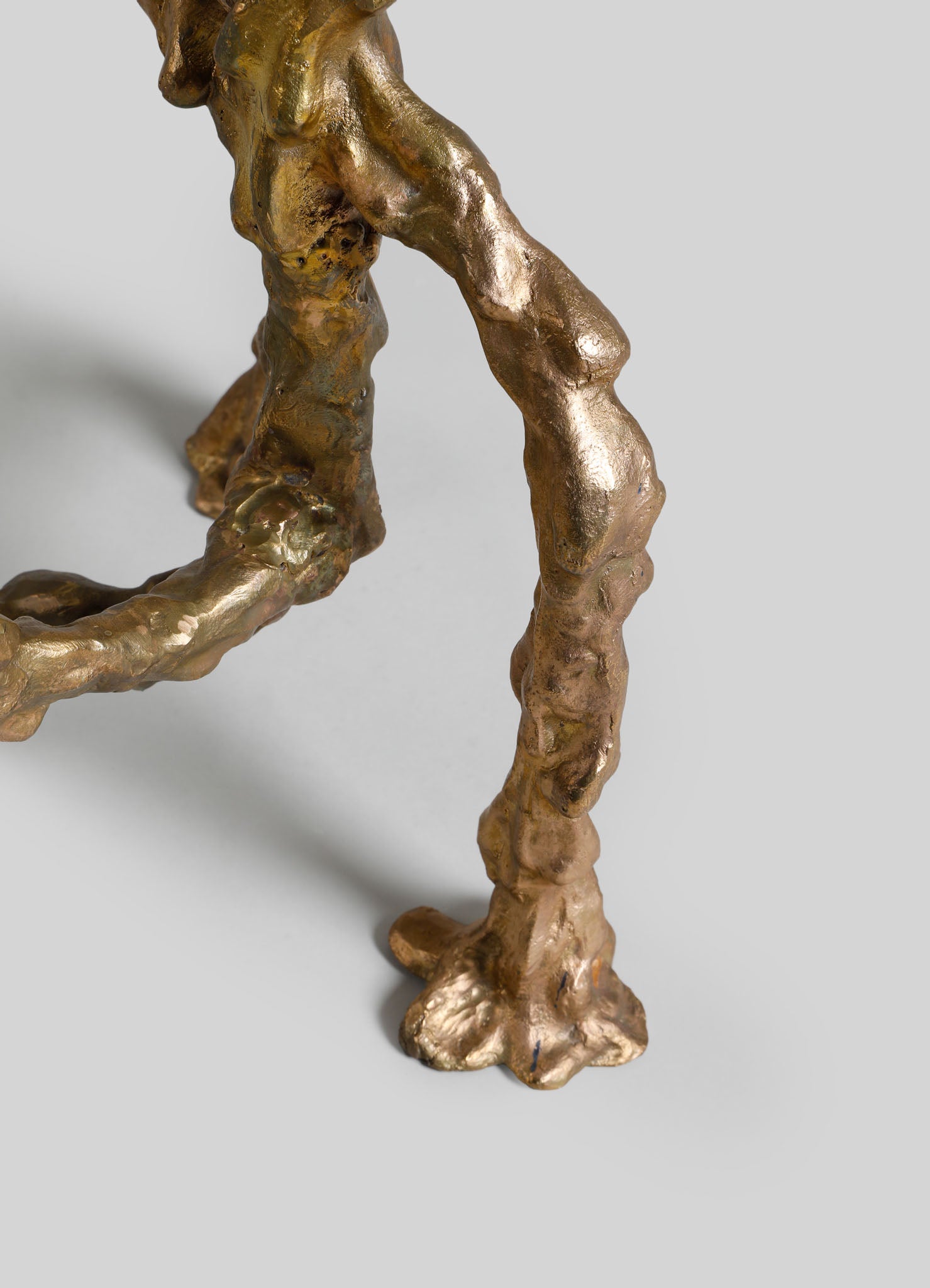 Bronze sculpture with a textured, organic form and a metallic gold finish, featuring irregular, flowing contours and a rustic style.