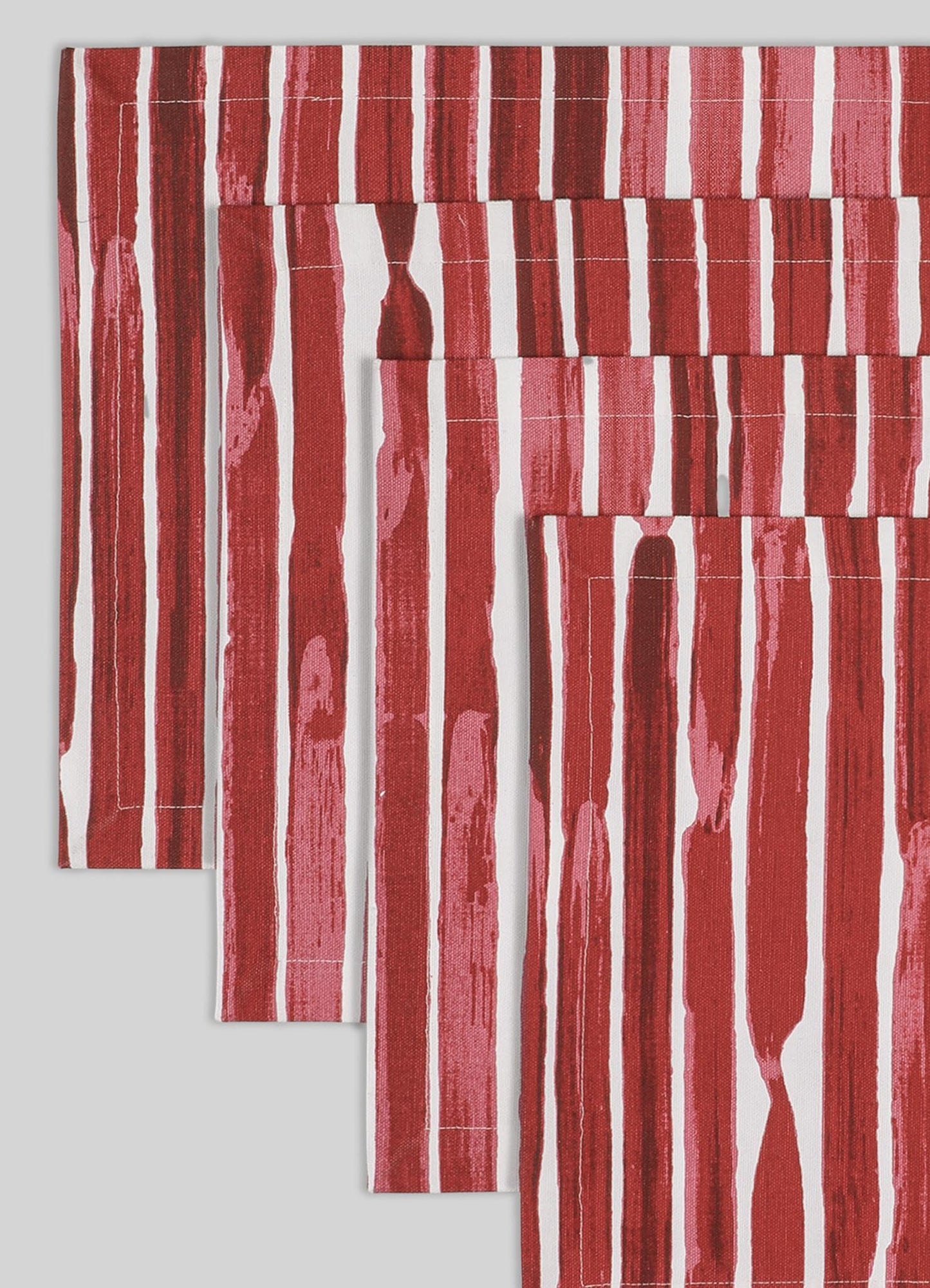 Cotton table linen set featuring bold red and white vertical stripe pattern, with a textured and handcrafted appearance. The fabric displays a mix of matte and slightly glossy finishes, emphasizing a contemporary design style.