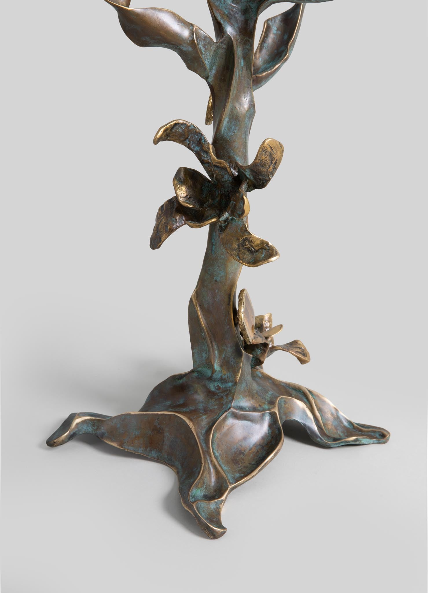 Bronze sculpture with organic, leaf-like motifs and a textured, patinated surface in tones of green and brown. The design emphasizes a natural, handcrafted style with flowing, sculptural forms.