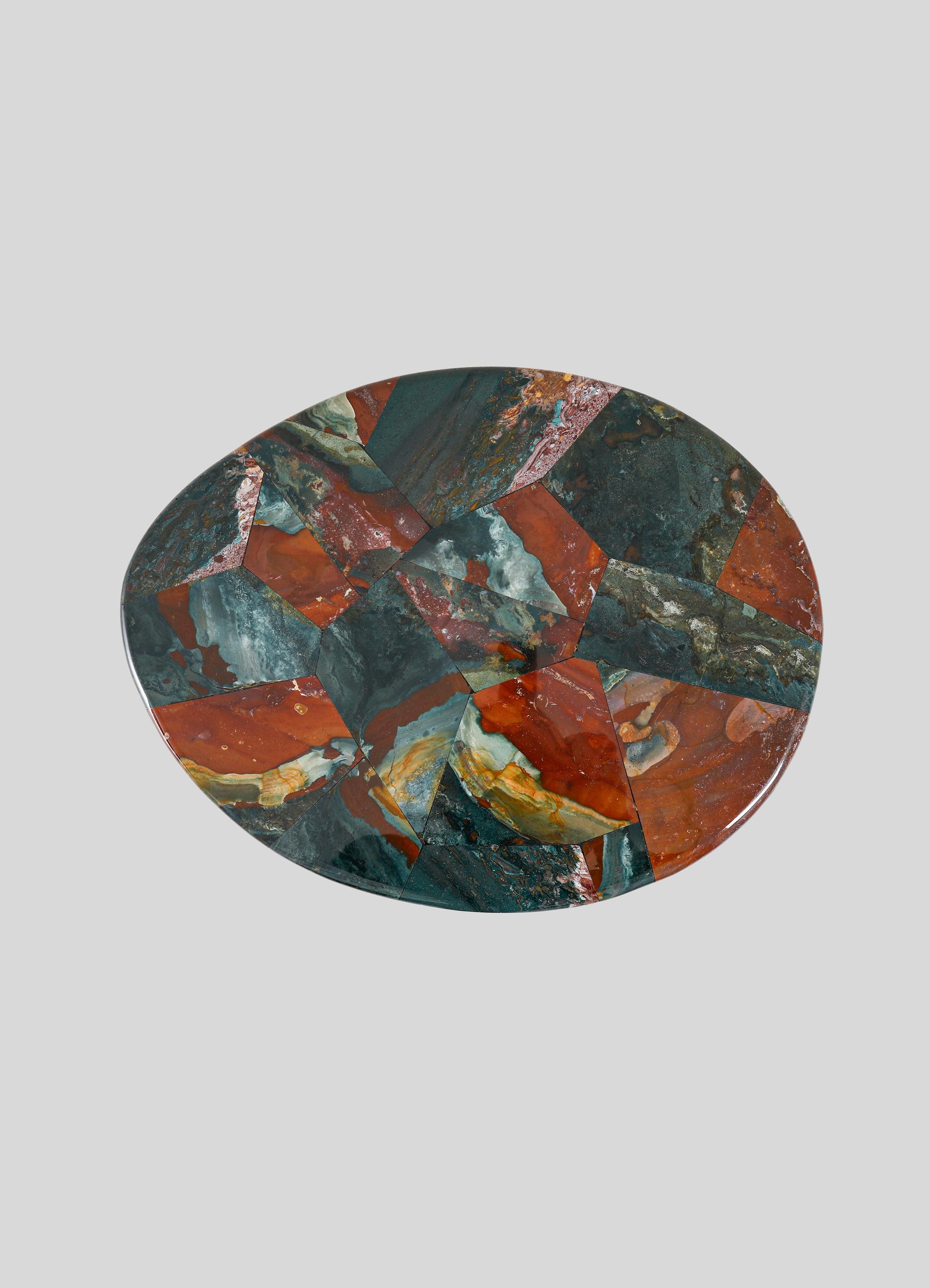The VIYA Under The Banyan Gold Side Table Large features a mosaic of red, green, and orange stone-like segments reminiscent of Banyan tree roots, displayed strikingly against a plain gray backdrop.