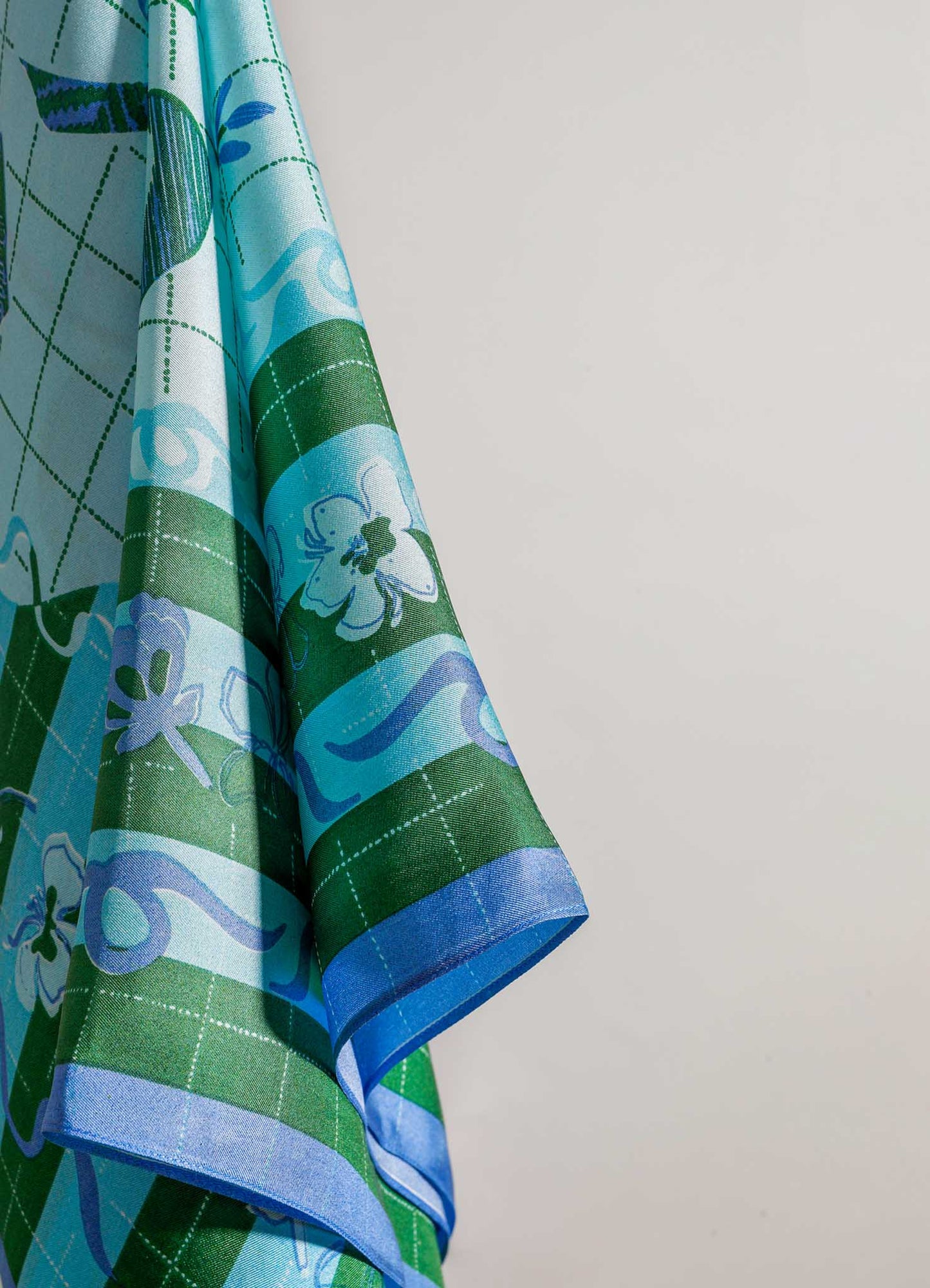 Fabric curtain with a floral pattern in shades of green, blue, and white, featuring geometric and vine motifs on a lightweight textile material.