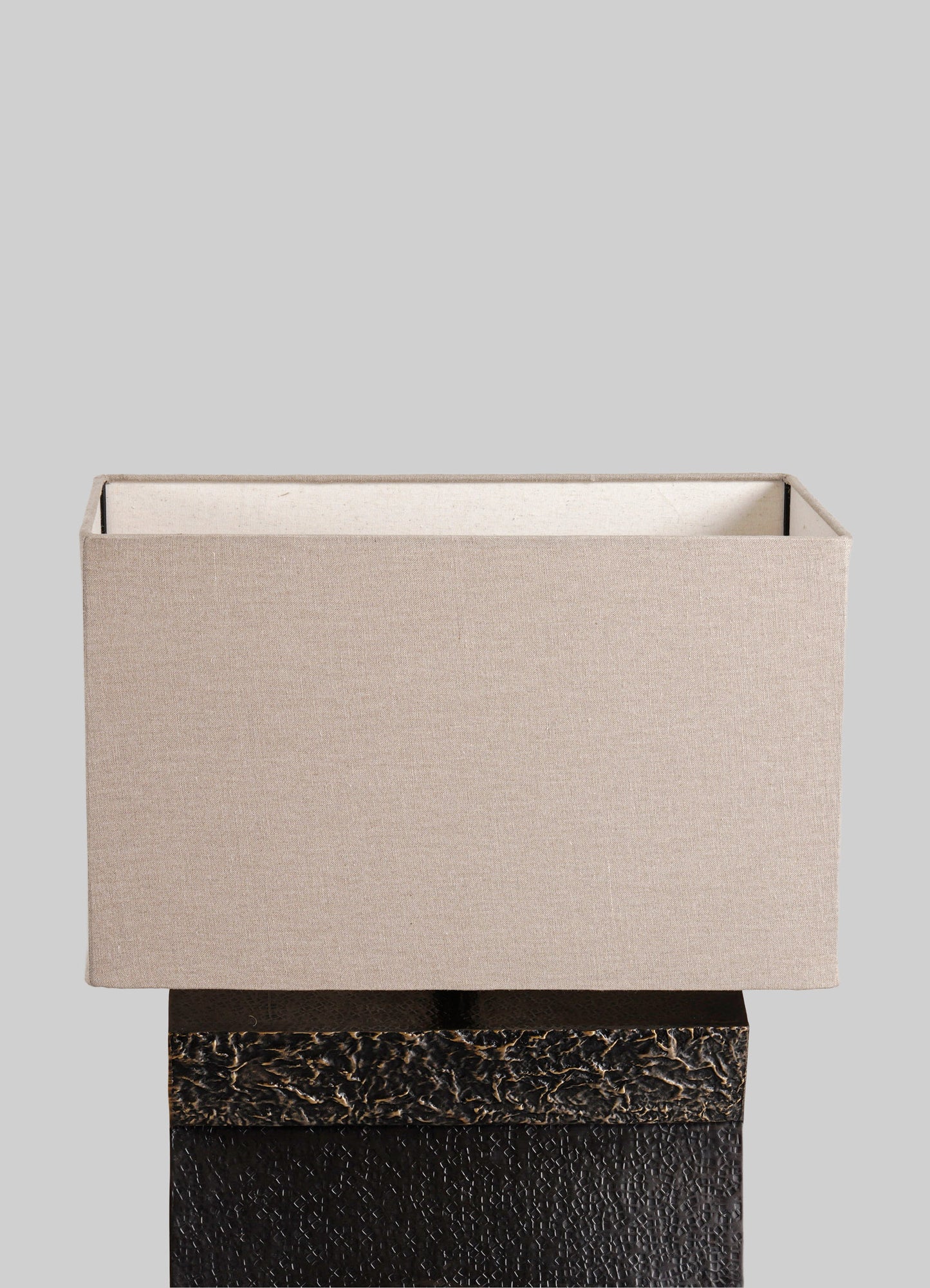 A rectangular fabric box with a beige exterior and a white interior, placed on a textured dark surface with a light gray background.