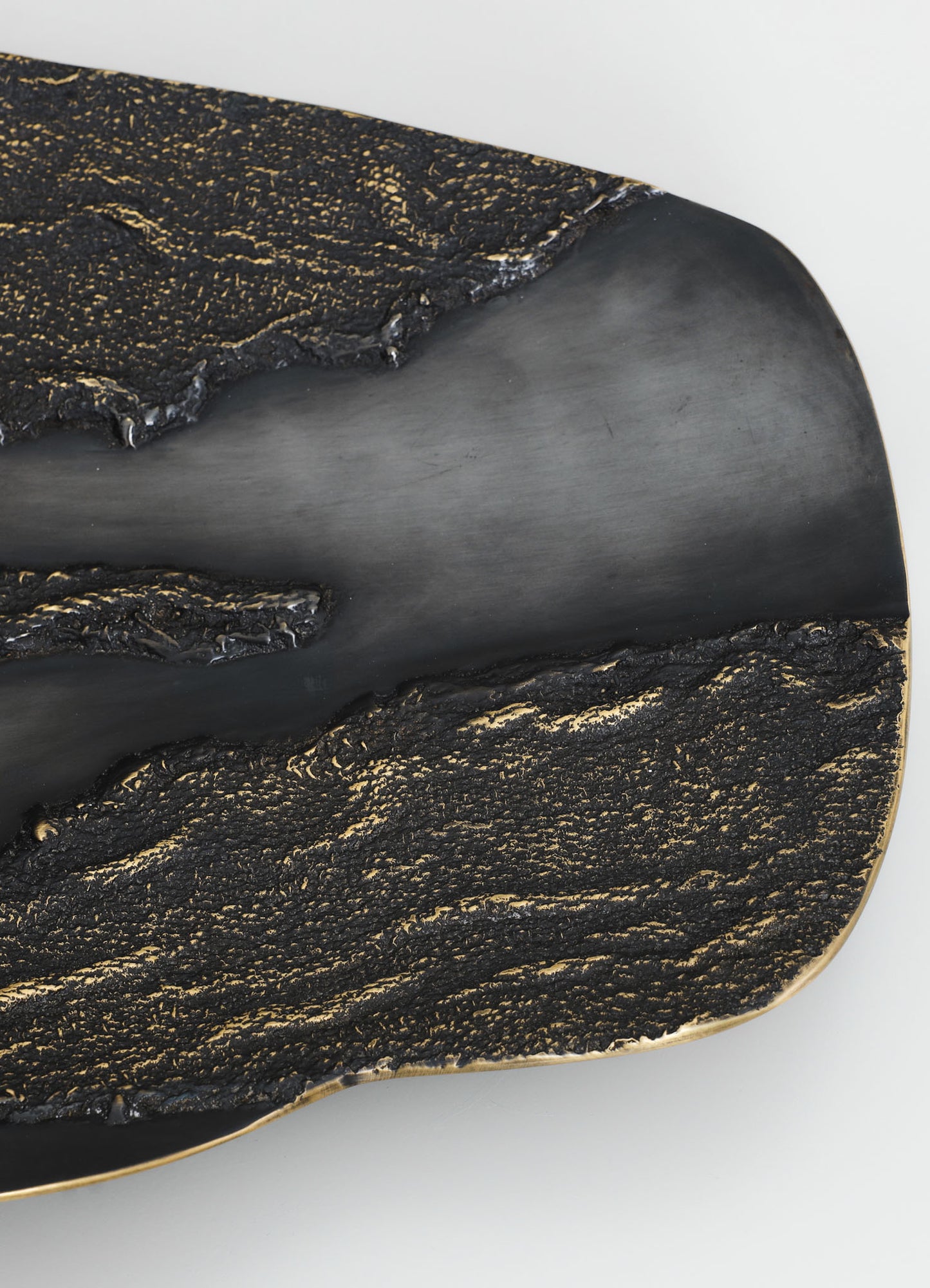 A decorative tray with a black, textured surface accented with gold details and a smooth, matte-black edge, featuring a contemporary style and metallic highlights.