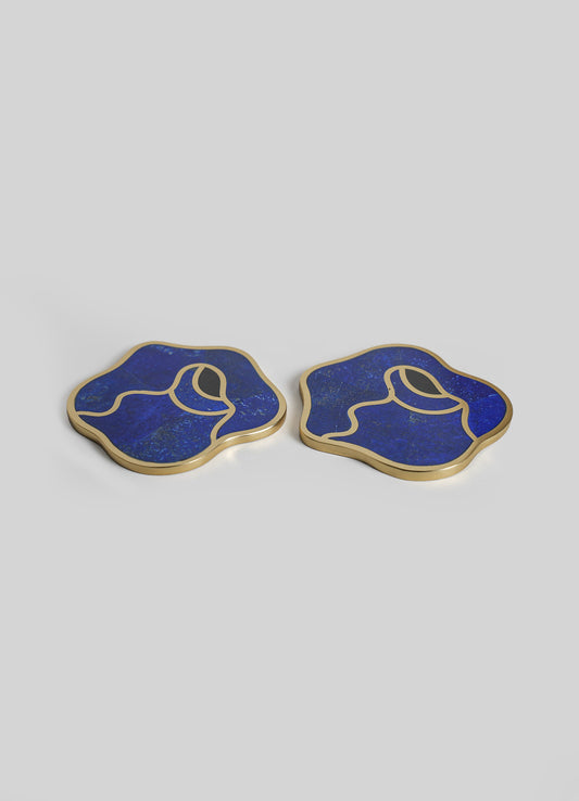 Pair of decorative coasters with irregular, abstract shapes, featuring deep blue resin with gold trim and fine speckled details.