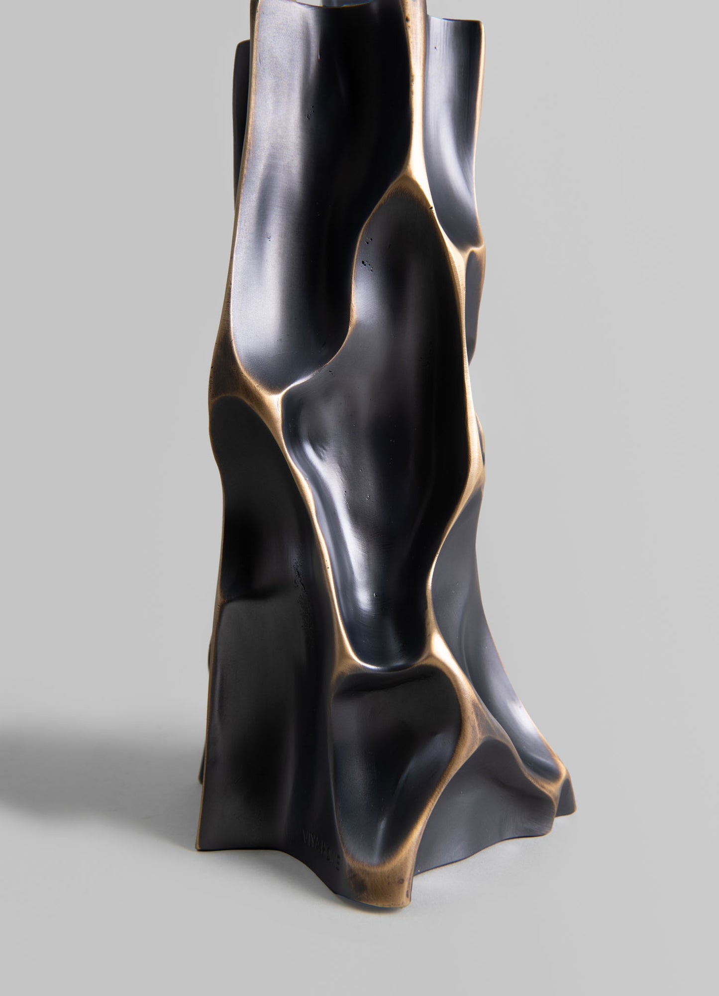 Sculptural decorative object with an organic, flowing form in matte black with metallic gold accents, possibly made of resin or ceramic, designed as a statement art piece for modern interiors.